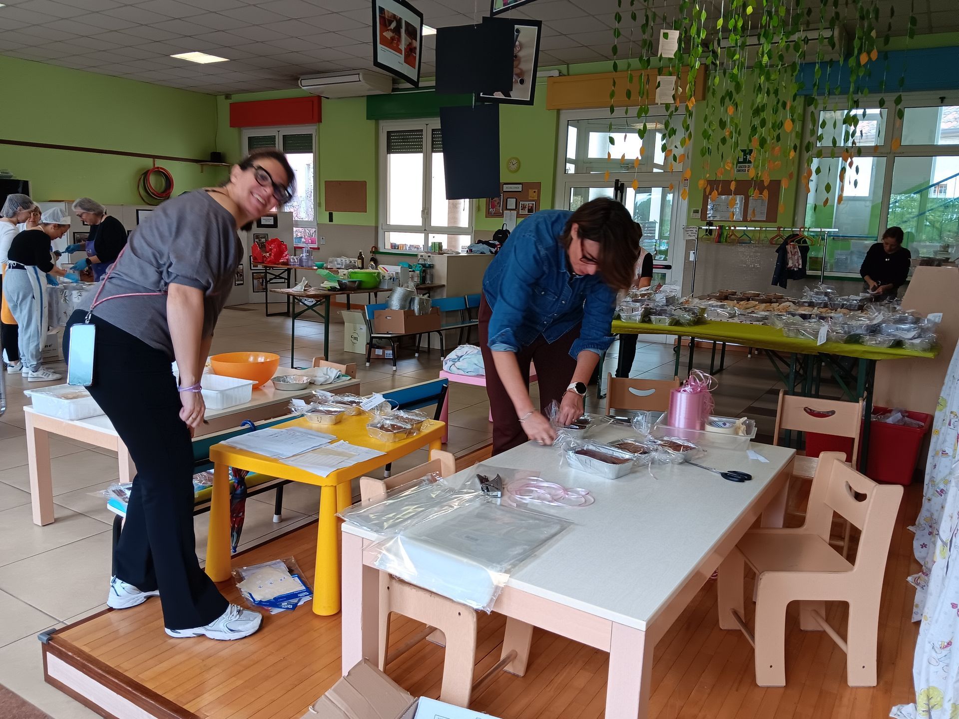 Persone intente a svolgere lavori manuali ai tavoli in un'aula o in uno studio luminoso.
