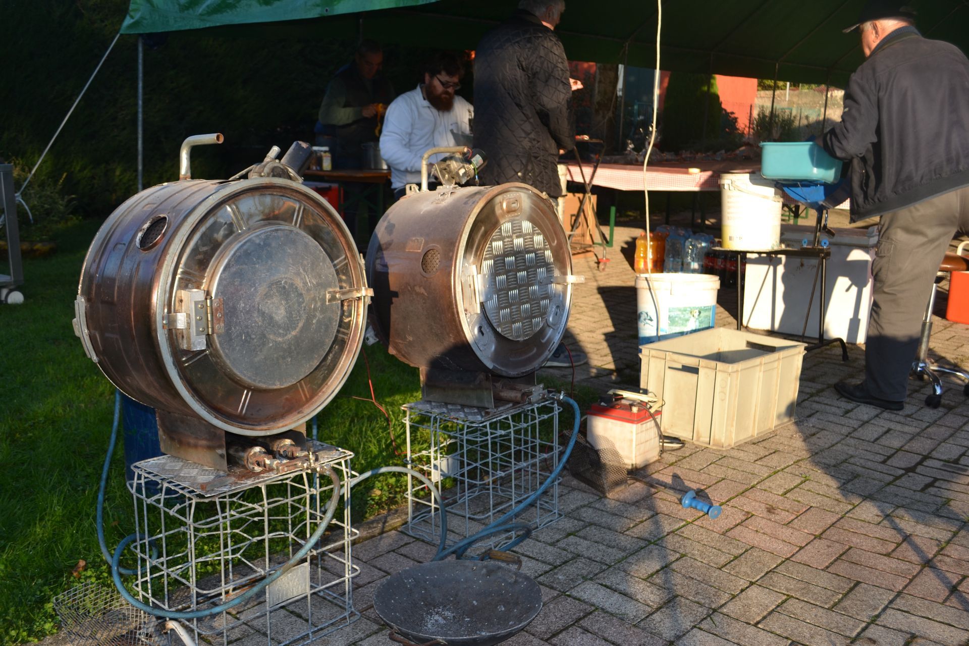 Due grandi griglie metalliche con cibo in un mercato all'aperto, persone che cucinano dietro di esse ai tavoli