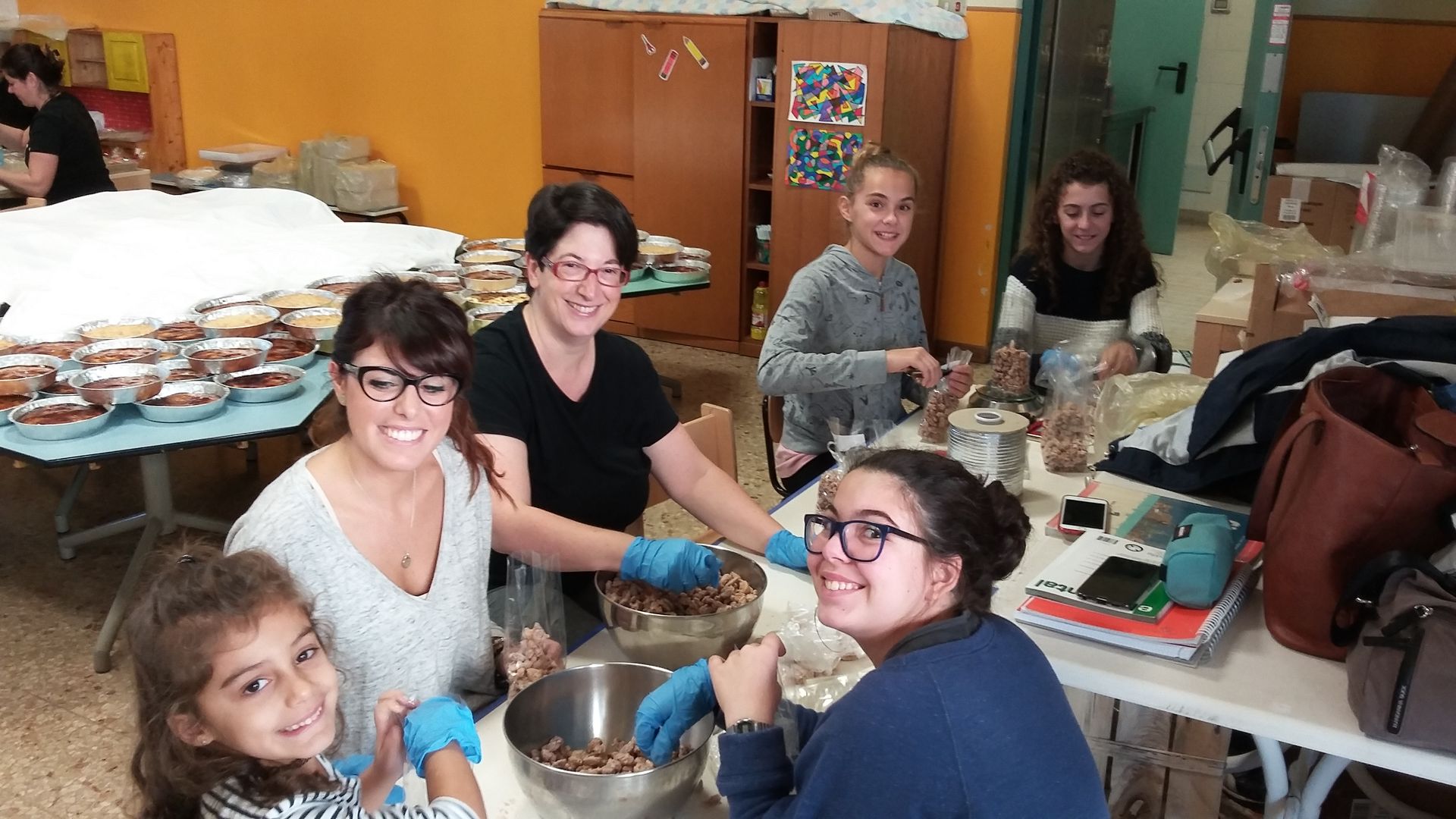 Persone riunite attorno a un tavolo da pranzo in una cucina accogliente, che condividono il cibo, sorridono e mangiano insieme.
