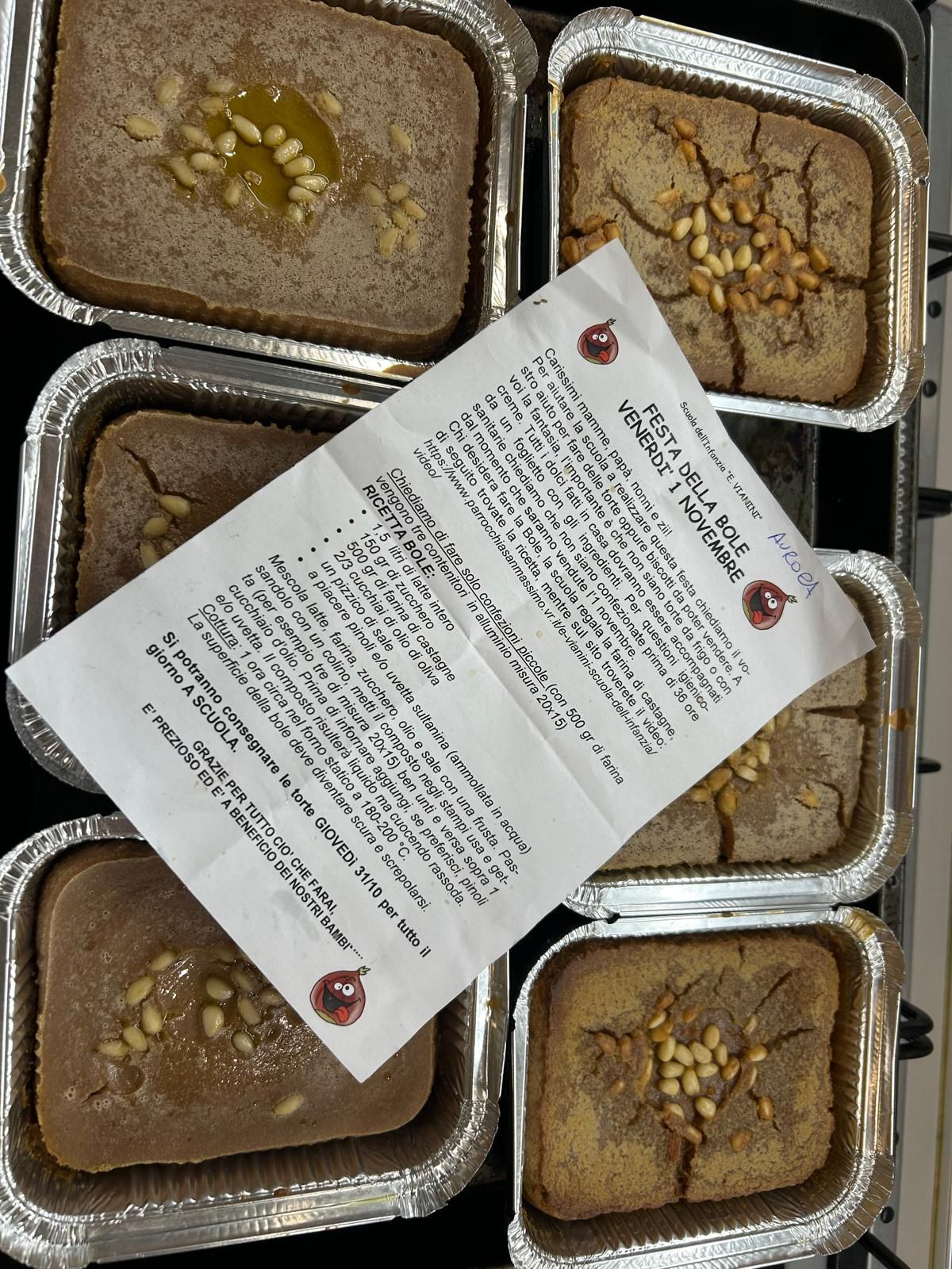 Sei vassoi di alluminio contenenti cibo, con sopra un menù stampato.