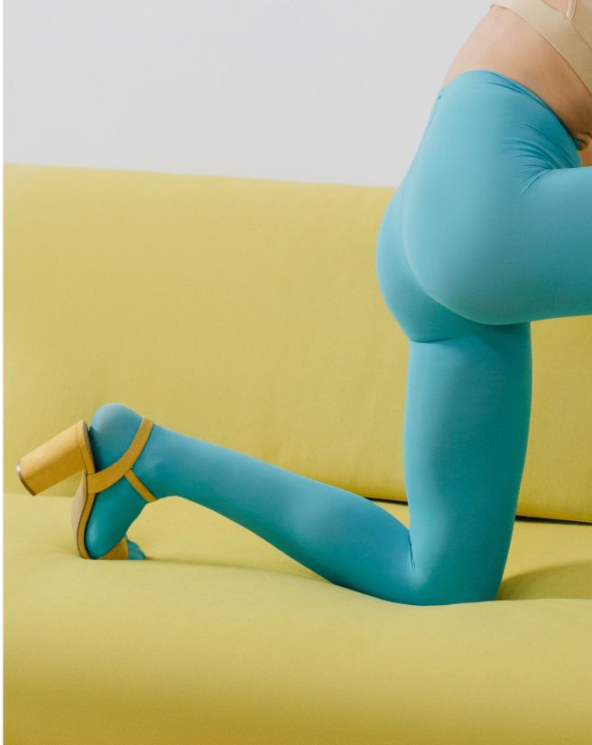 Een persoon knielt op een gele bank, draagt ​​een blauwe legging en een gele schoen.