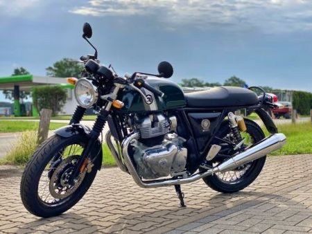 A green motorcycle is parked on a brick sidewalk.