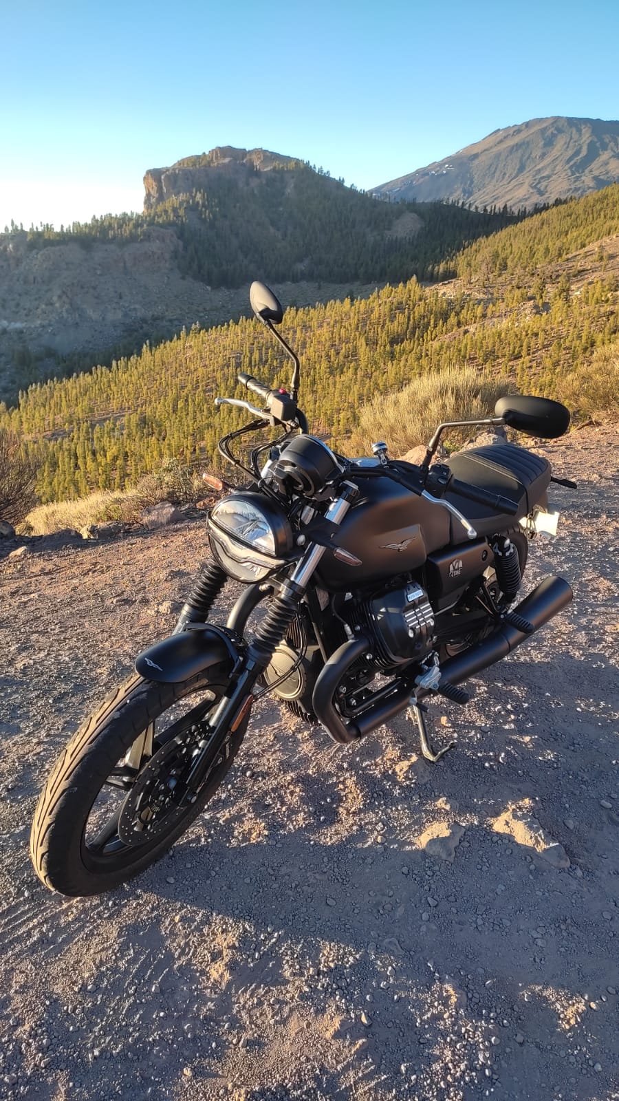 A motorcycle is parked on the side of a dirt road.