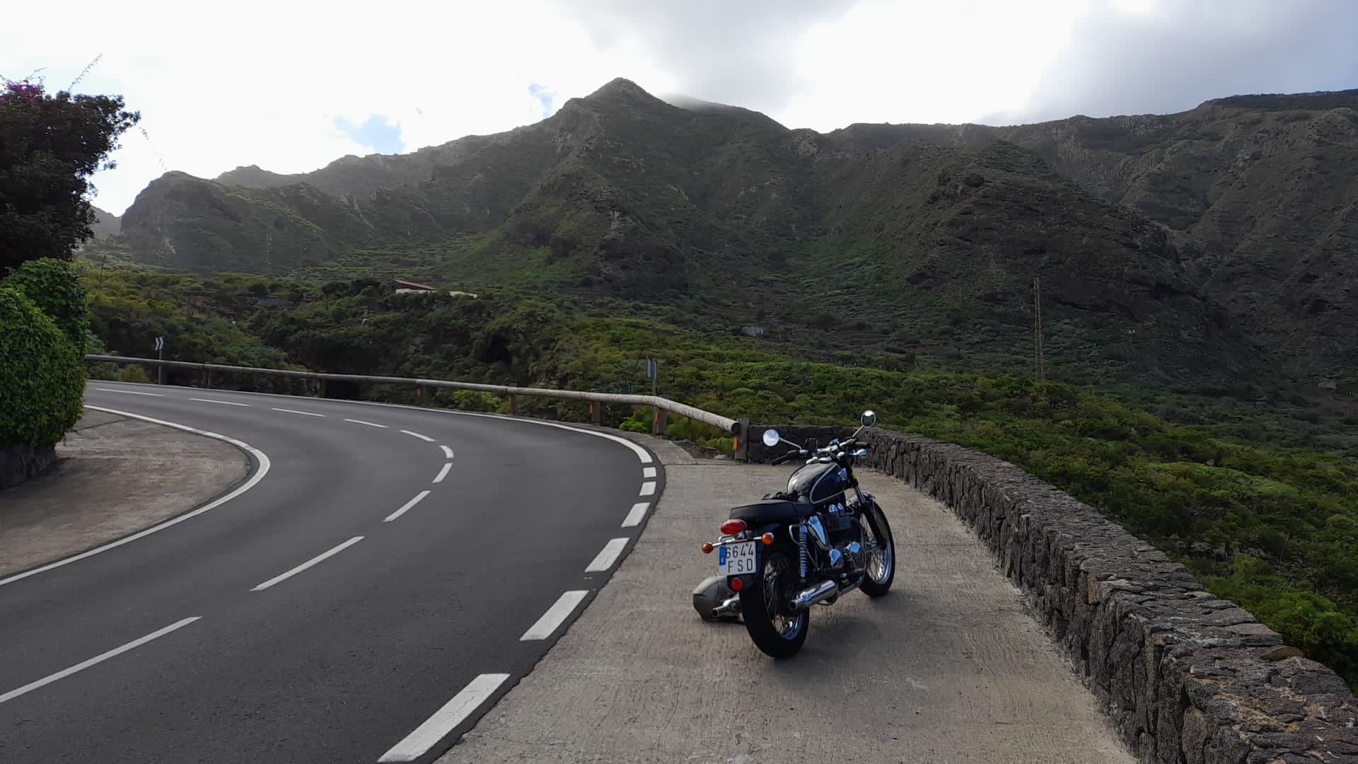 A motorcycle is parked on the side of a curvy road.