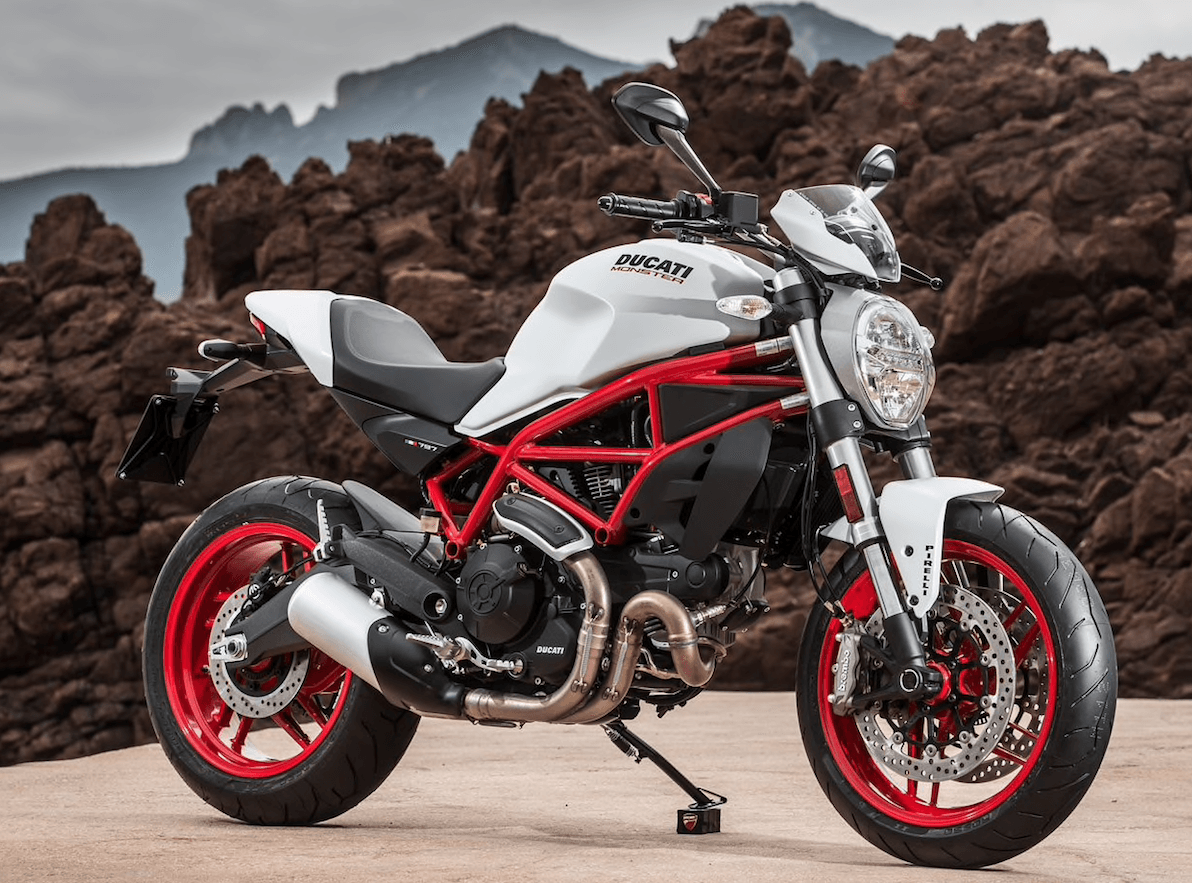 A white and red ducati monster motorcycle is parked on the side of the road.