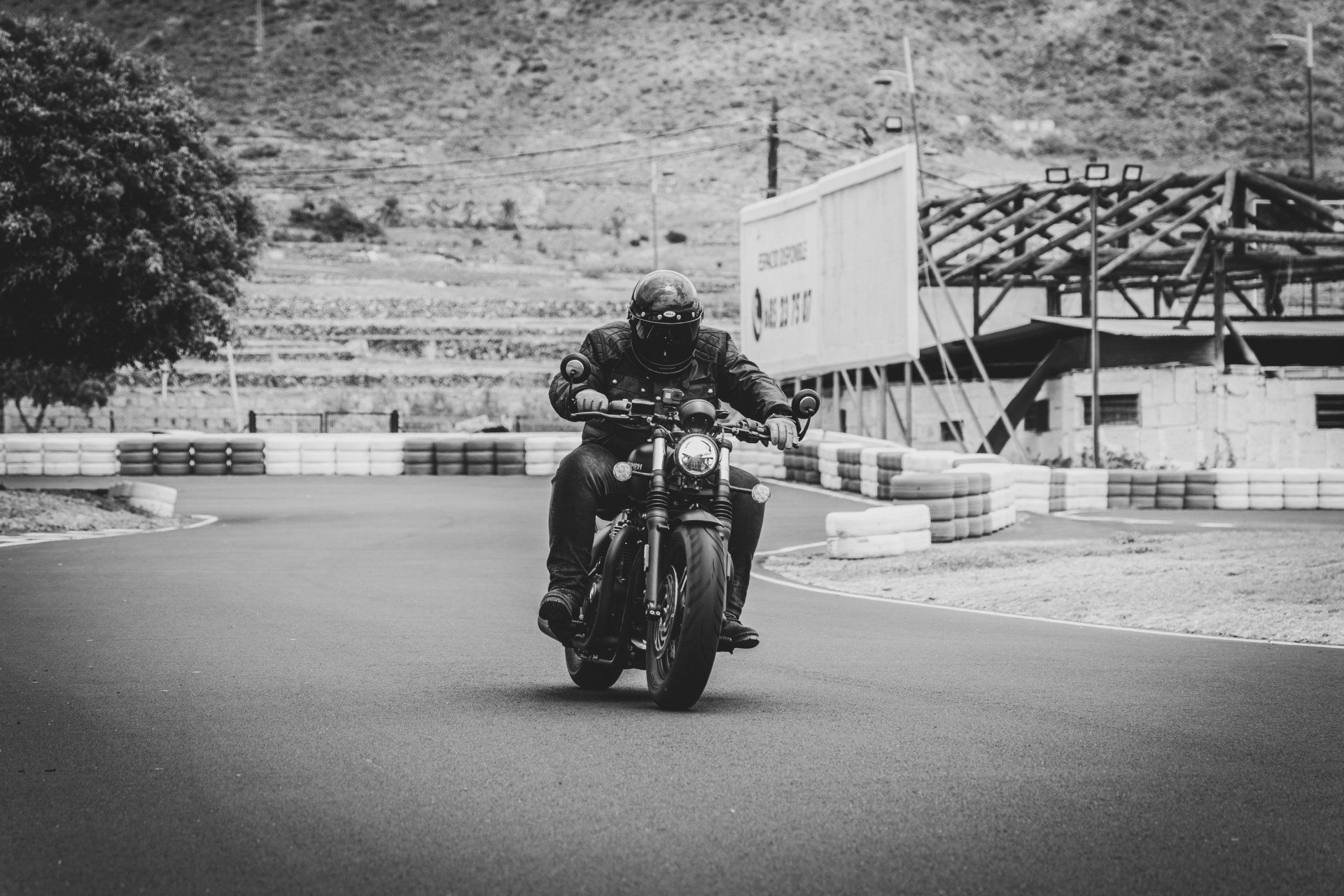 A black and white photo of a man riding a motorcycle
