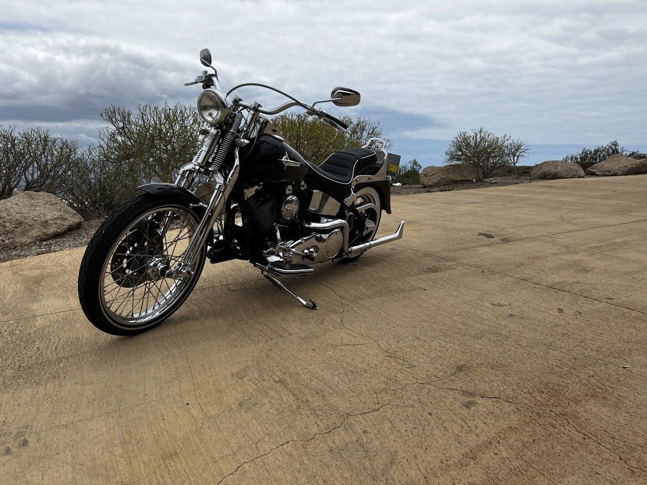 A black motorcycle is parked on the side of a dirt road.