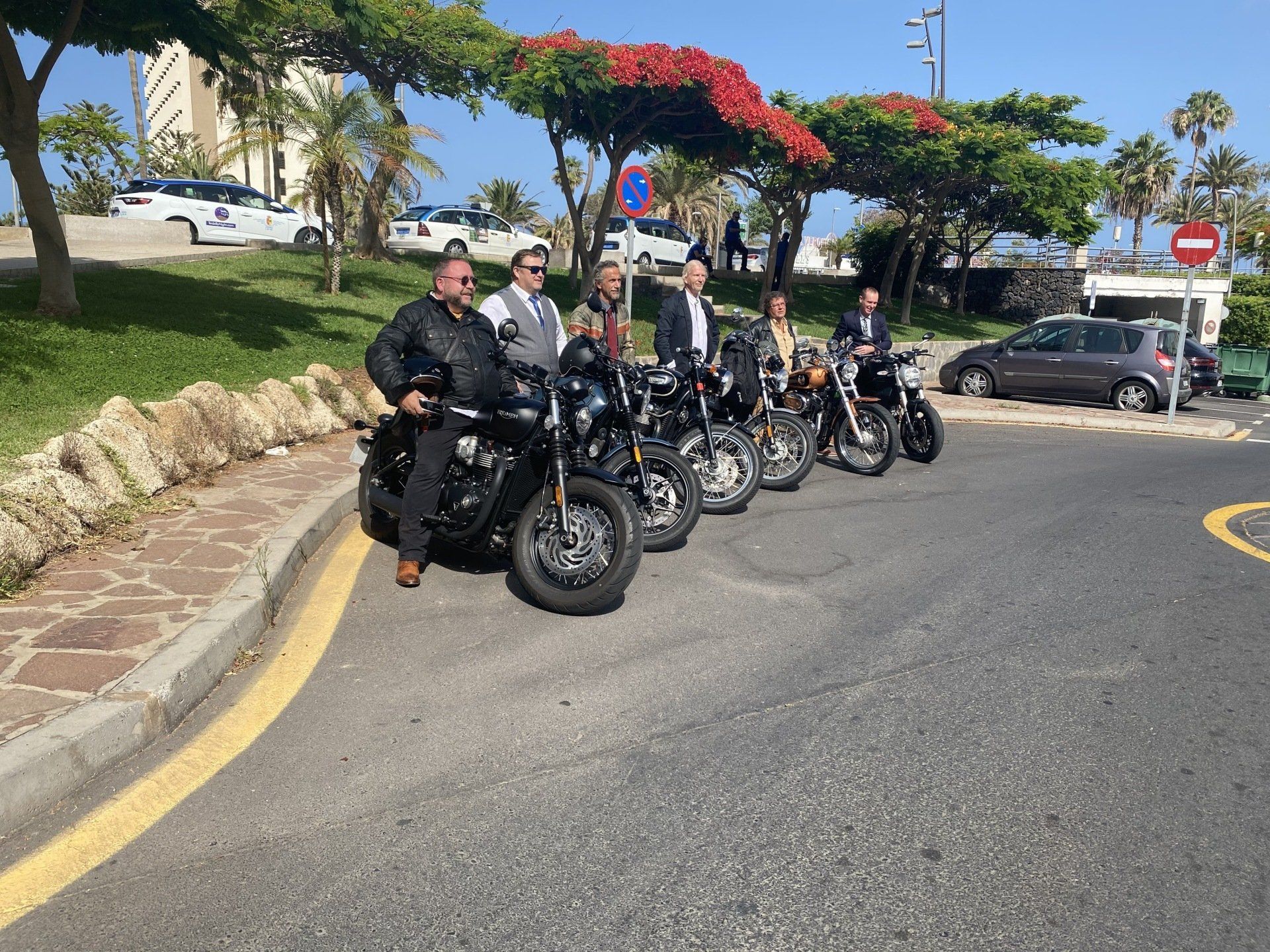 A group of people are standing next to their motorcycles on the side of the road.