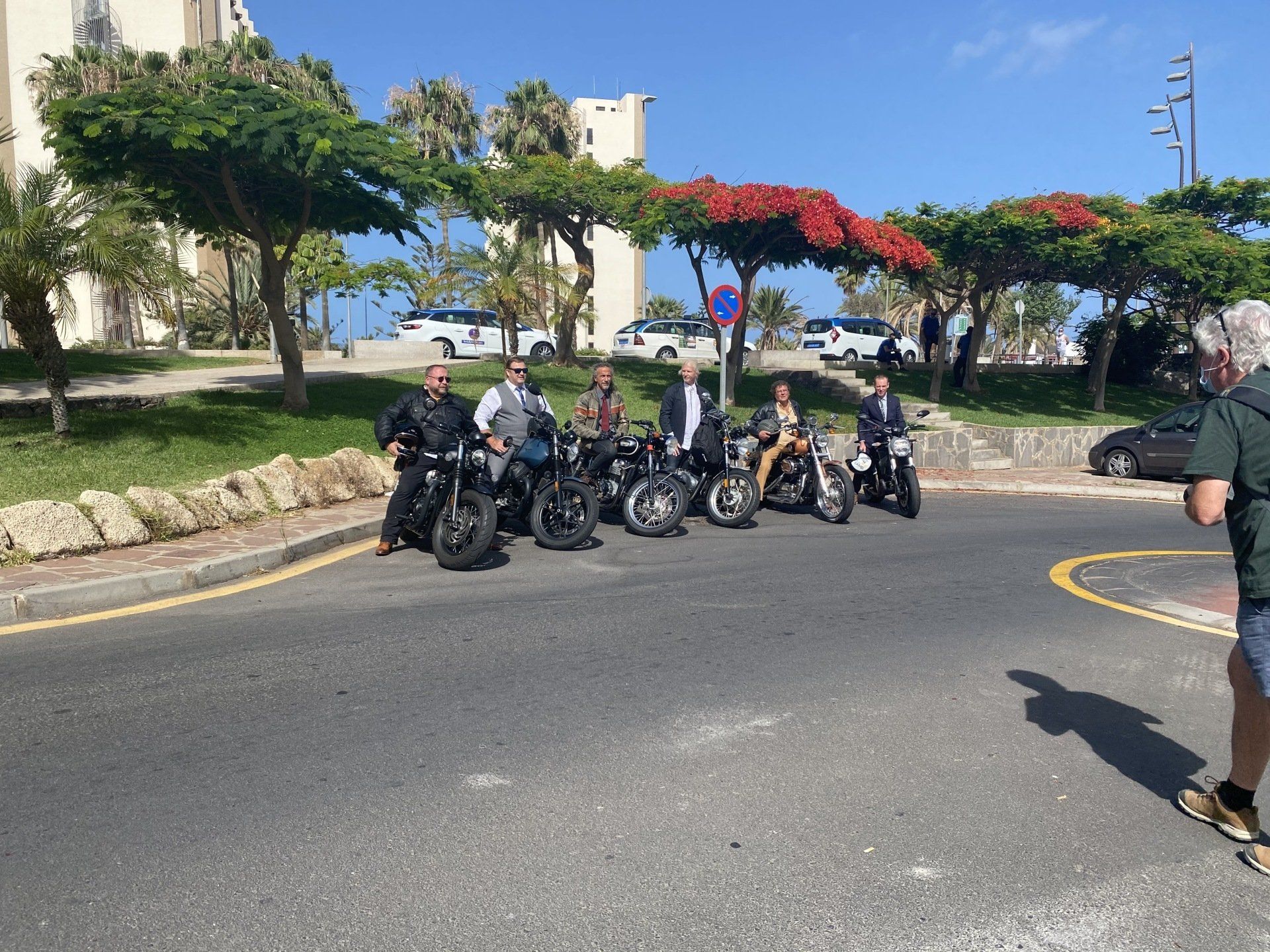 A group of men are sitting on motorcycles on the side of the road.