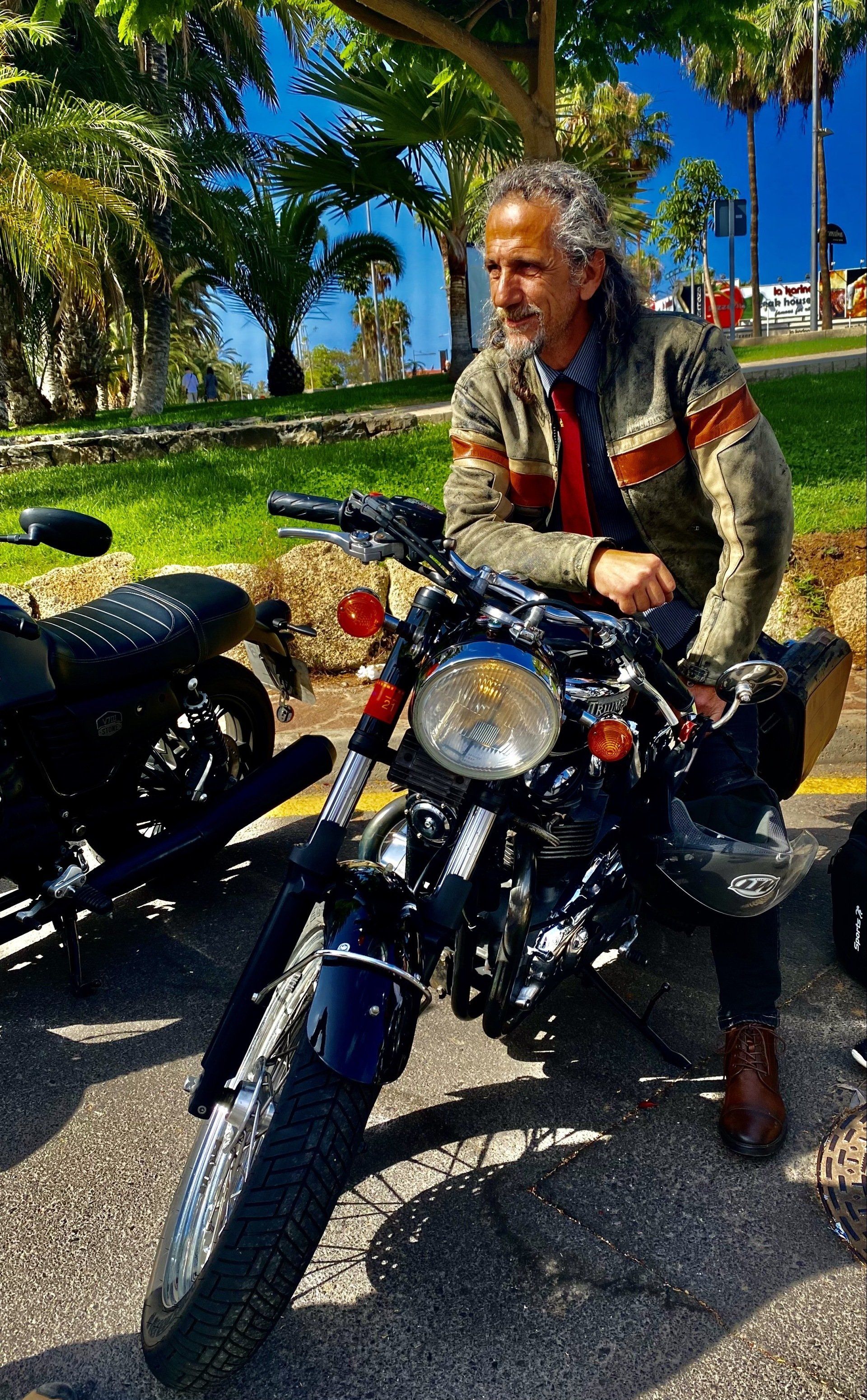 A man is sitting on a motorcycle in a park.