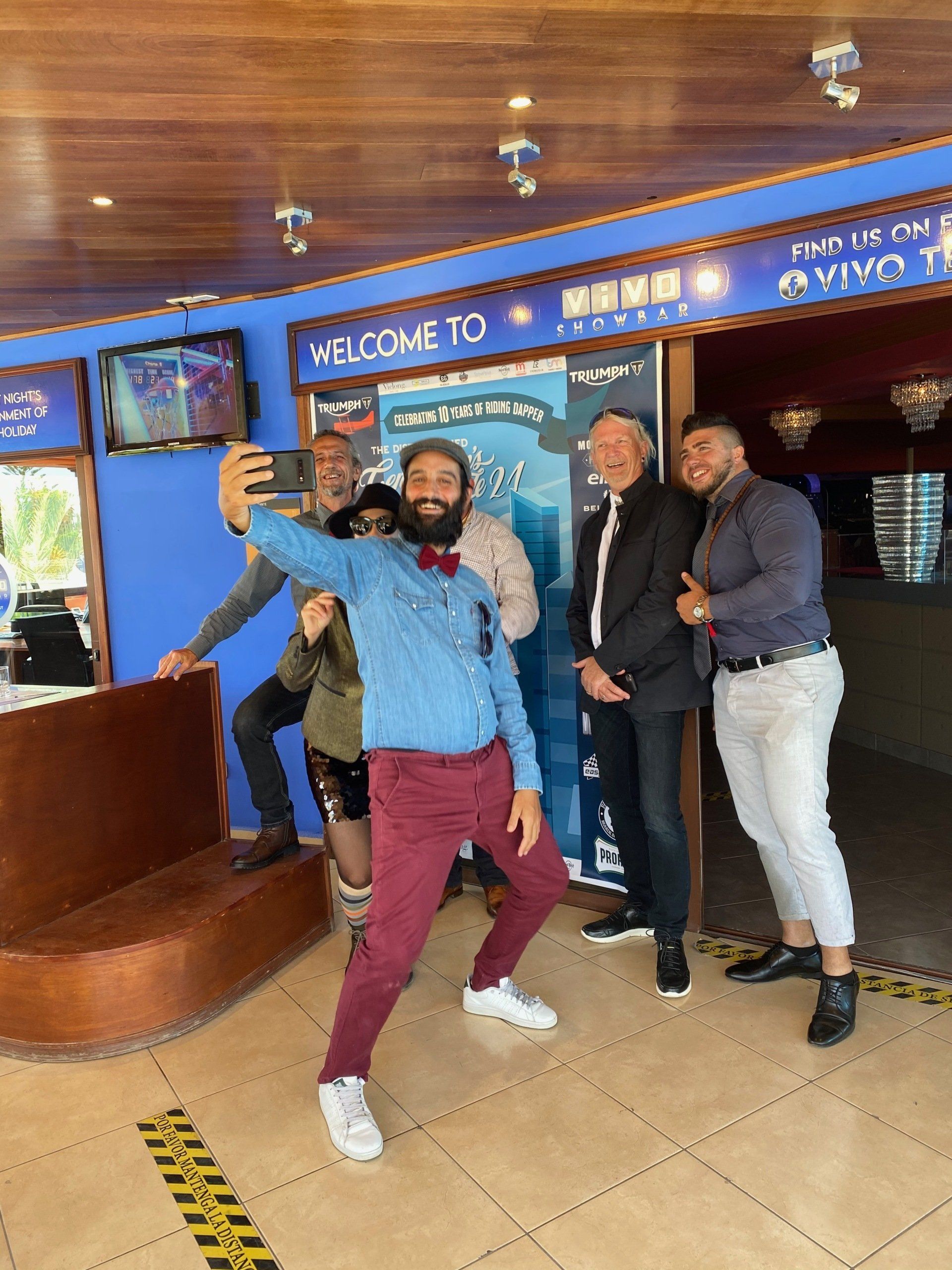 A group of men are taking a selfie in a restaurant.