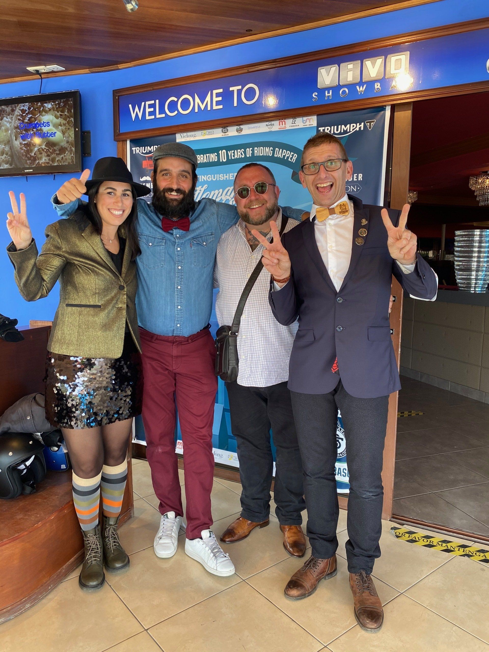 A group of people are posing for a picture in front of a welcome sign.