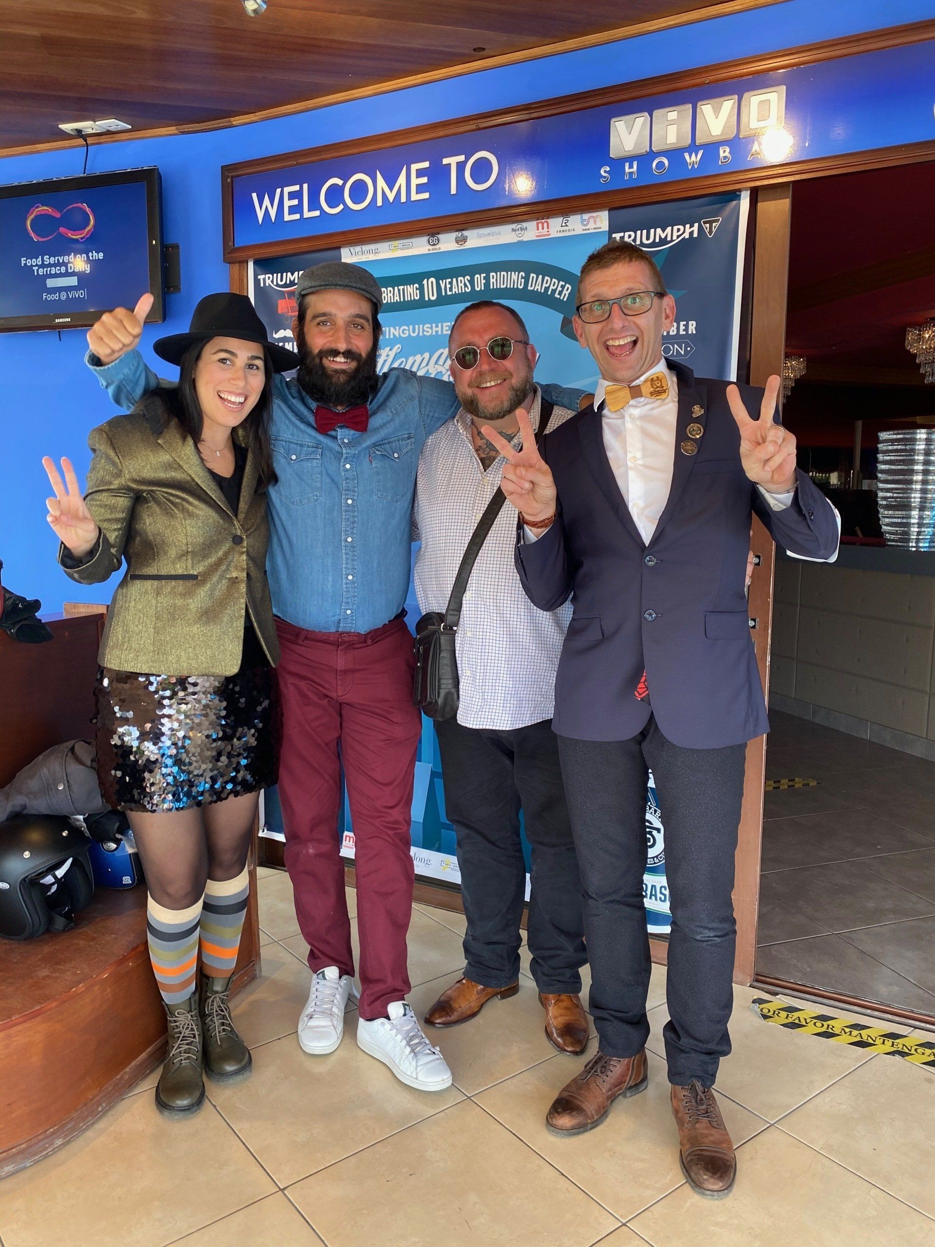 A group of people are posing for a picture in front of a sign that says welcome to.
