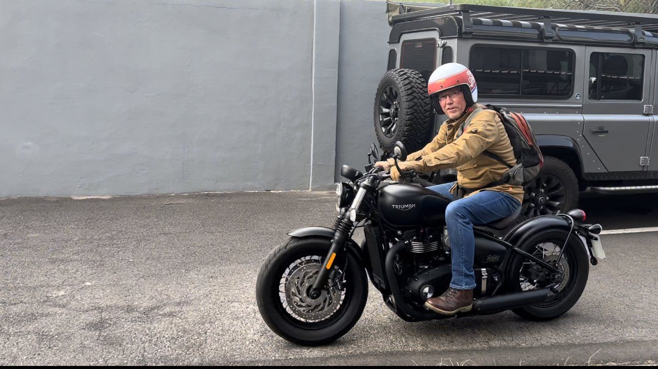 A man is riding a motorcycle in a parking lot.