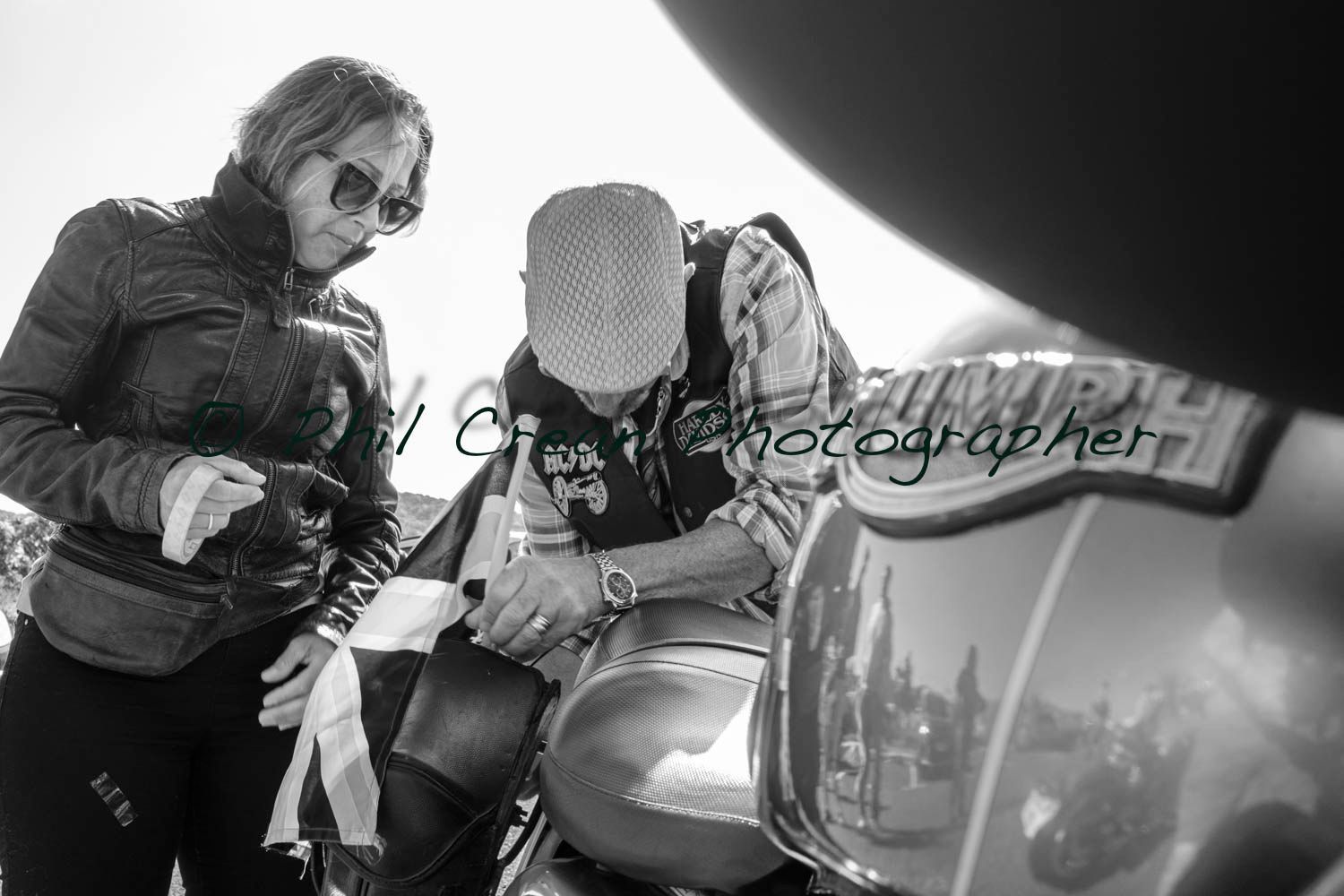 A man and a woman are standing next to a triumph motorcycle.