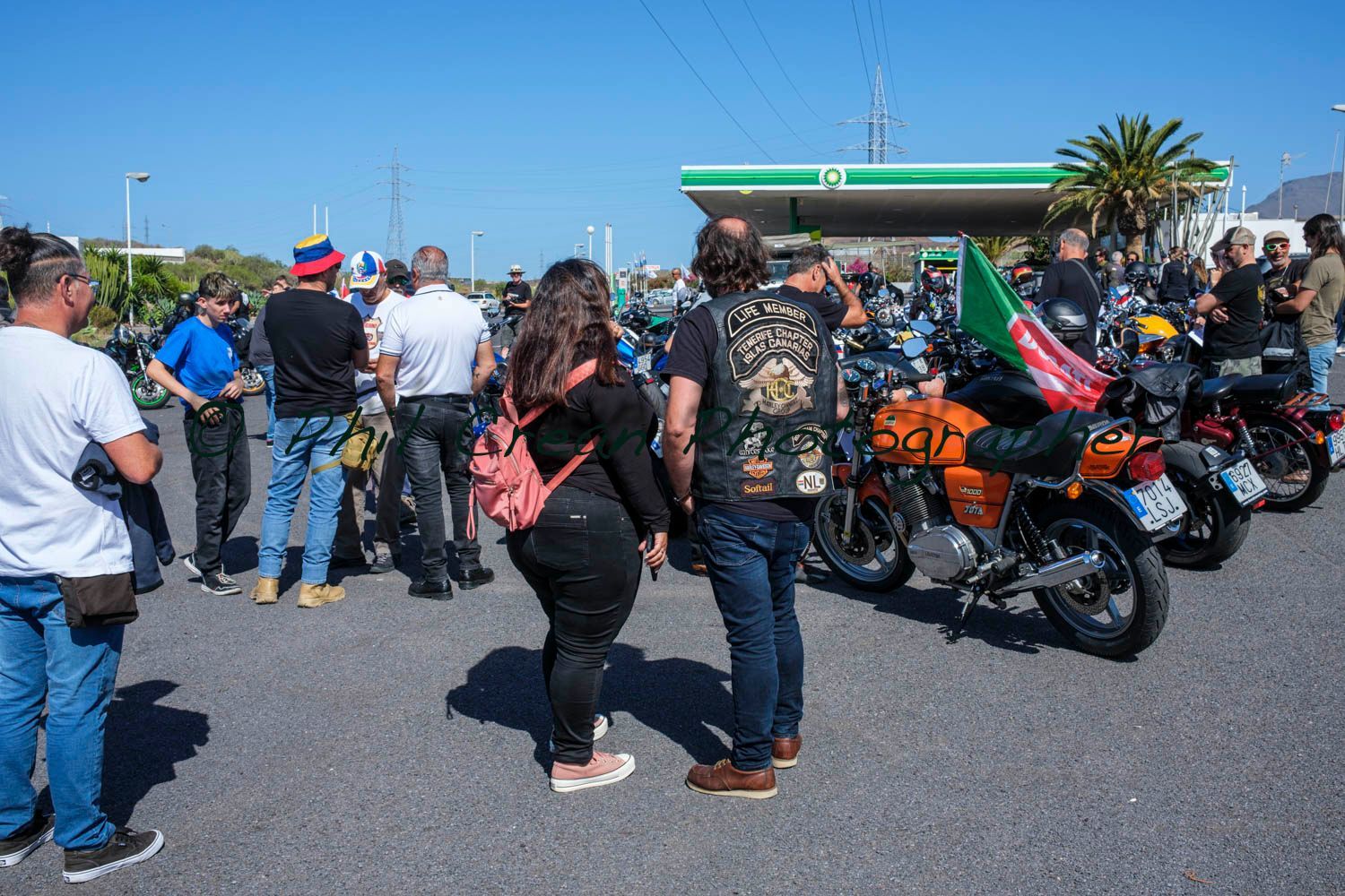 A group of people are standing in front of a gas station.