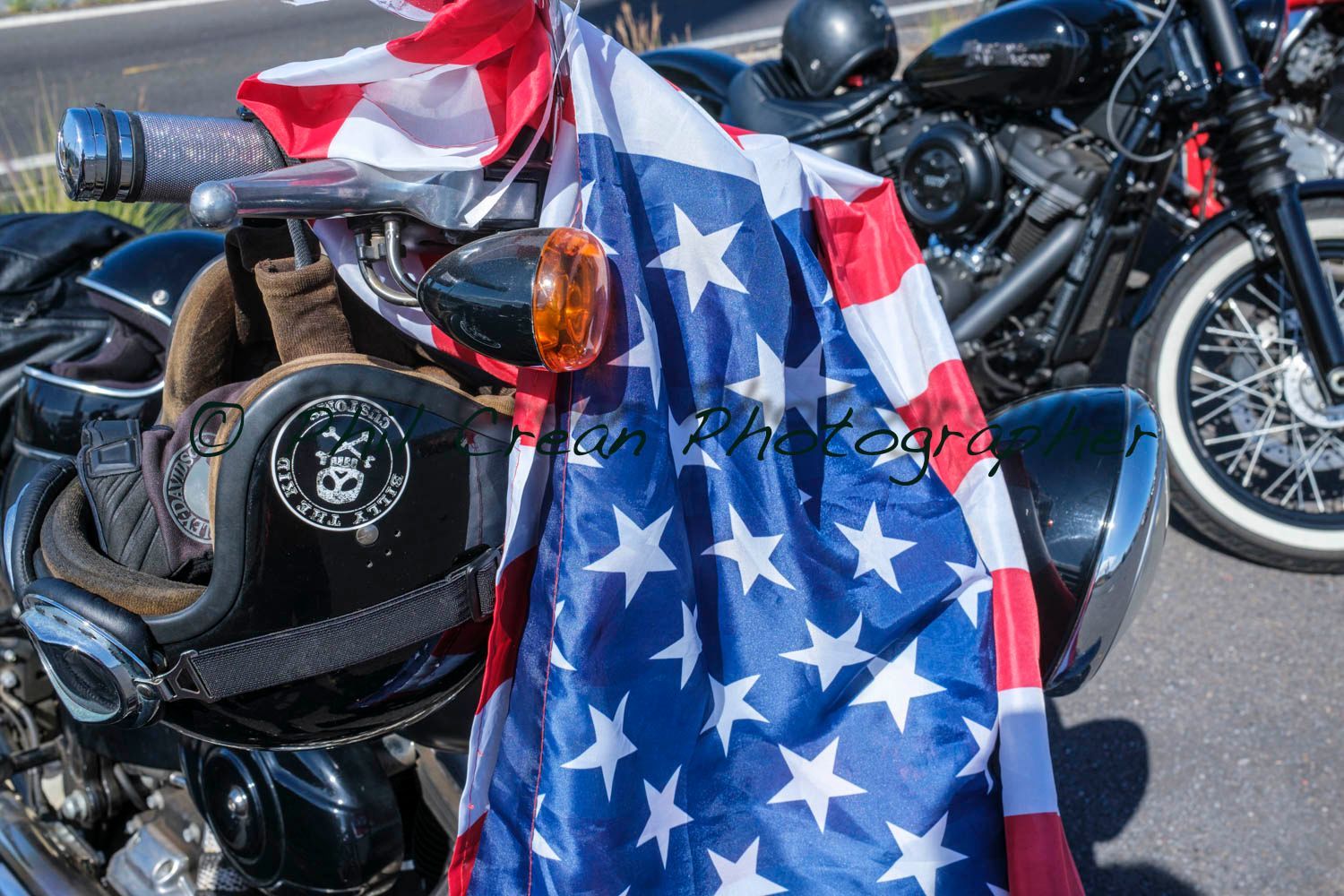 A person is holding an american flag in front of a motorcycle.