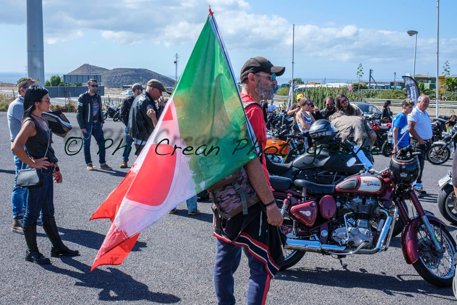 A man is holding a flag in front of a row of motorcycles.