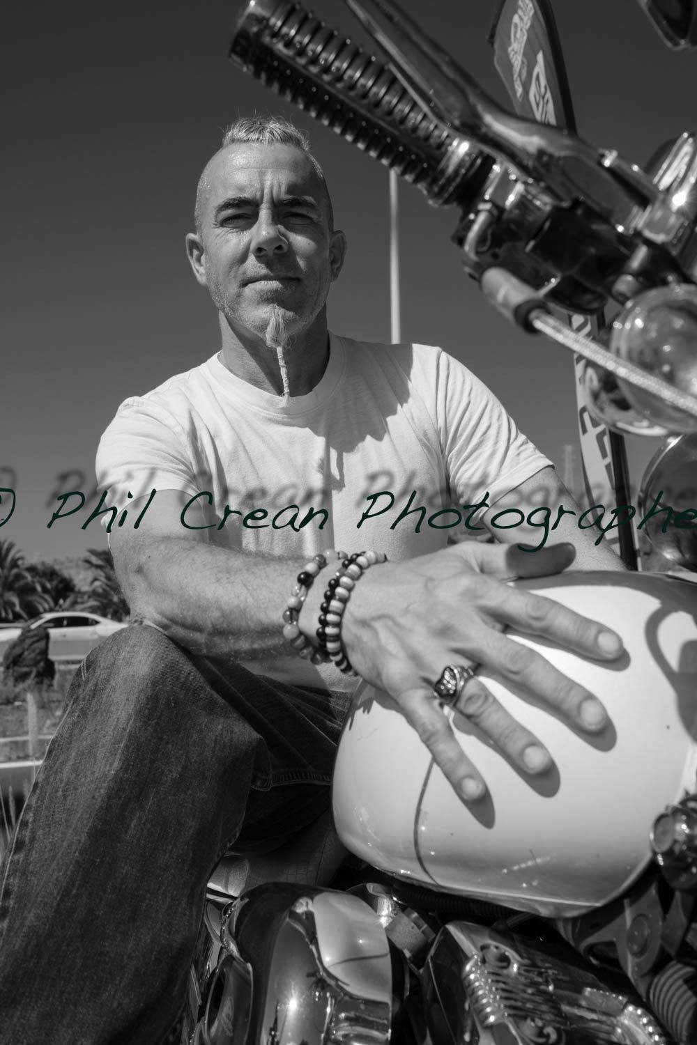 A man is sitting on a motorcycle with his hand on the tank