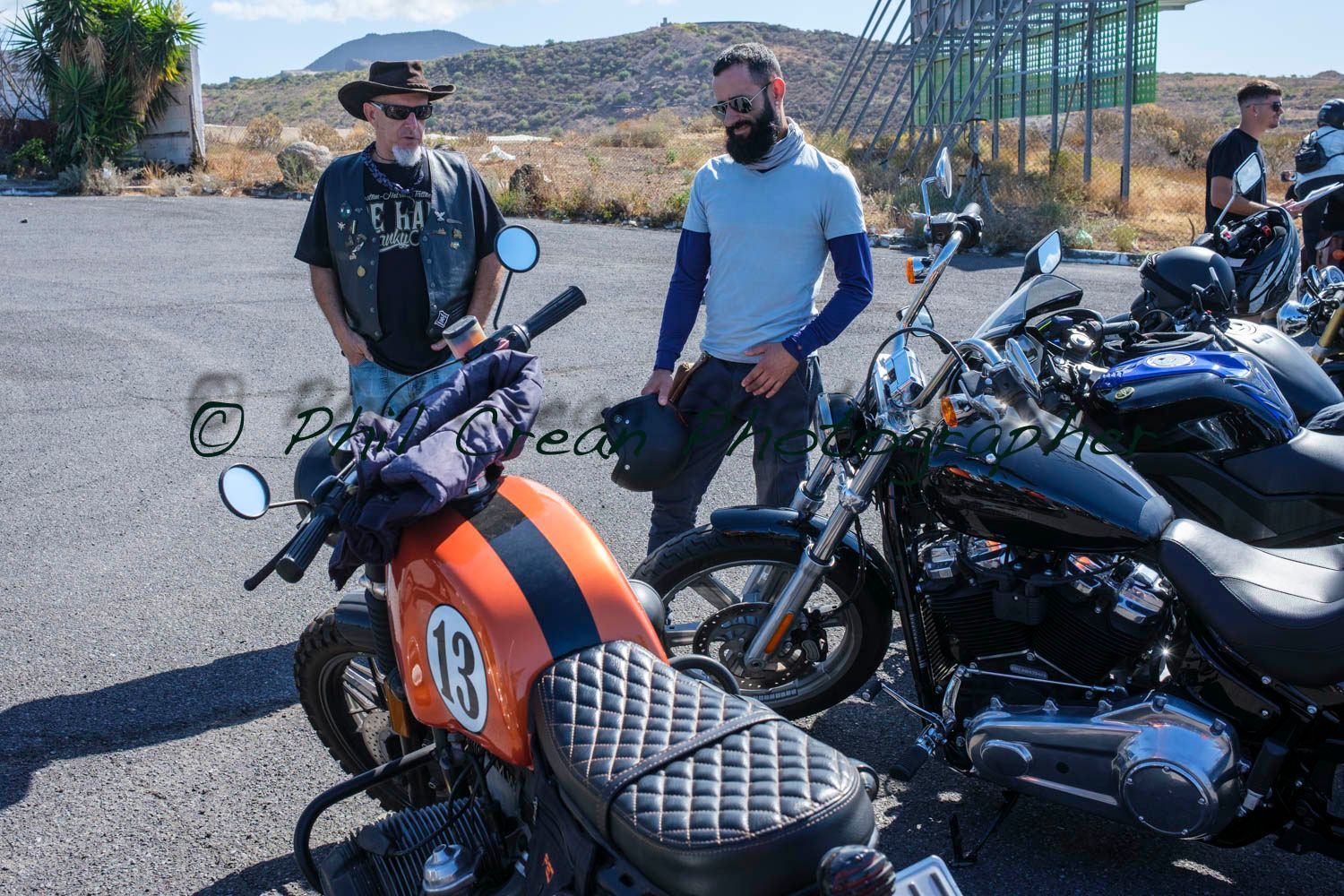 Two men are standing next to a motorcycle with the number 13 on it.