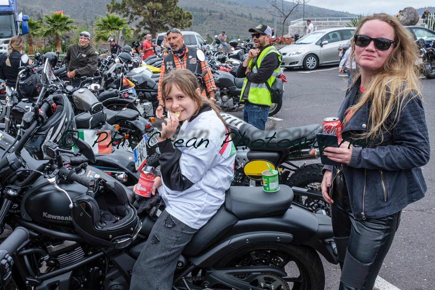 Two women are standing next to a motorcycle in a parking lot.