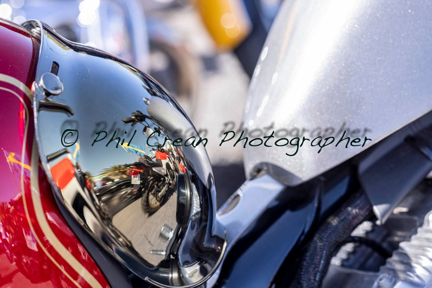 A reflection of a motorcycle in the side mirror of a red motorcycle