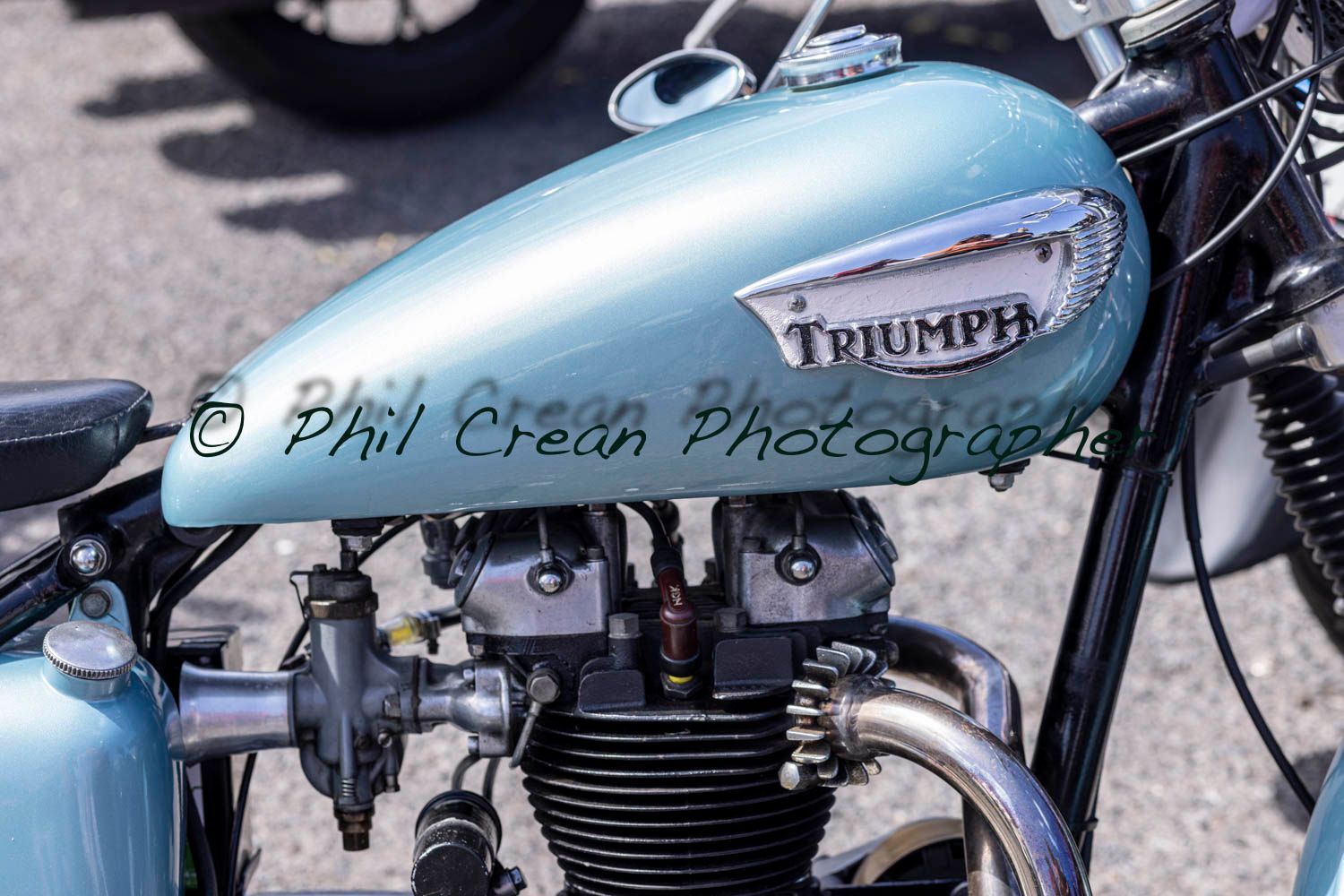 A blue triumph motorcycle is parked on the street