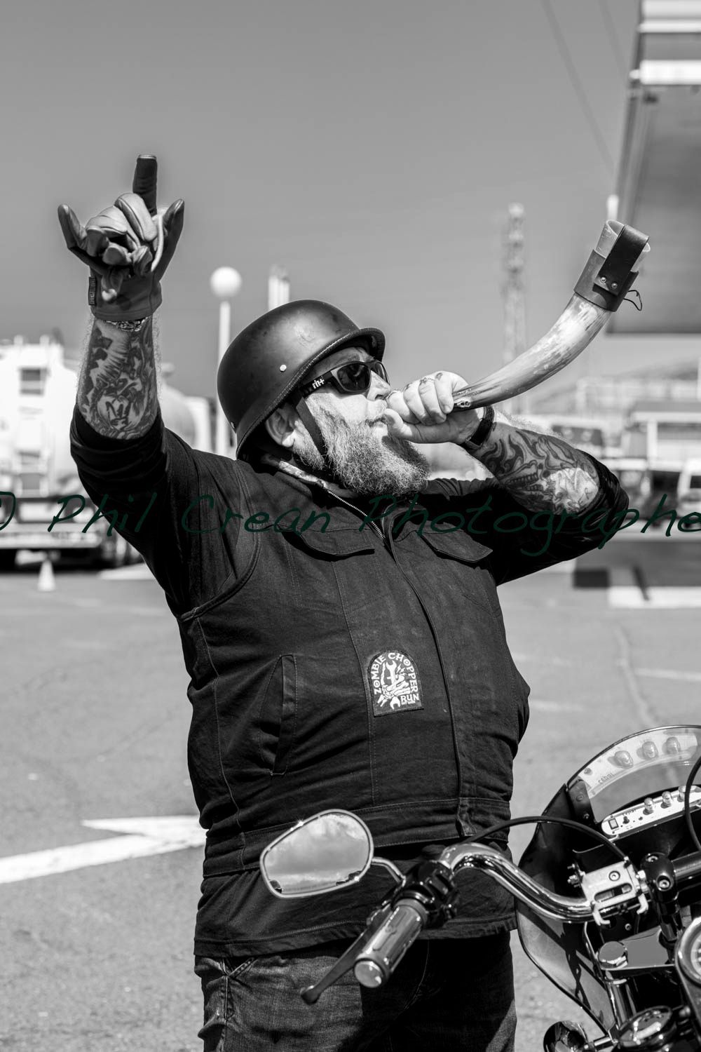 A man on a motorcycle is blowing a horn in a black and white photo.