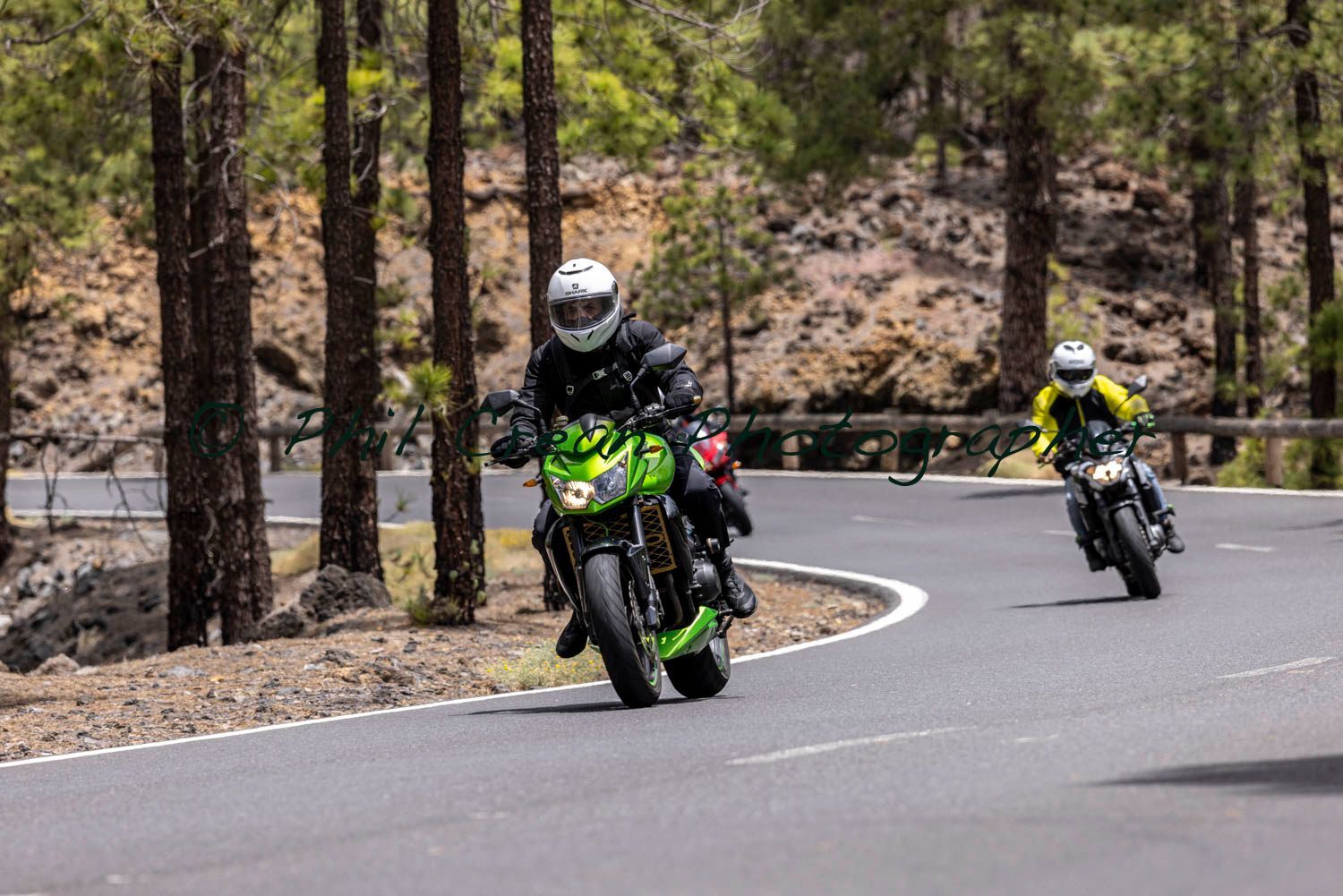 Two men are riding motorcycles down a curvy road.