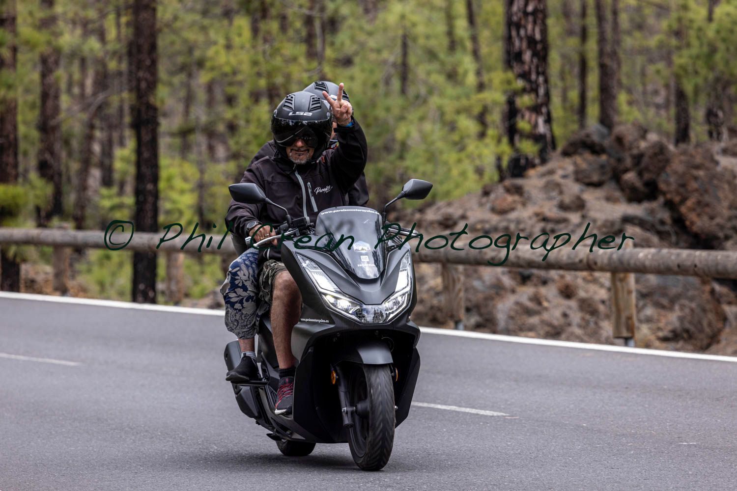 A man is riding a motorcycle down a road.