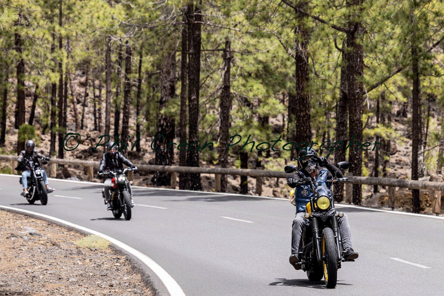 A group of people are riding motorcycles down a road.