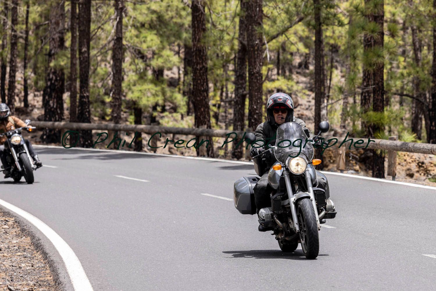 Two people are riding motorcycles down a curvy road.