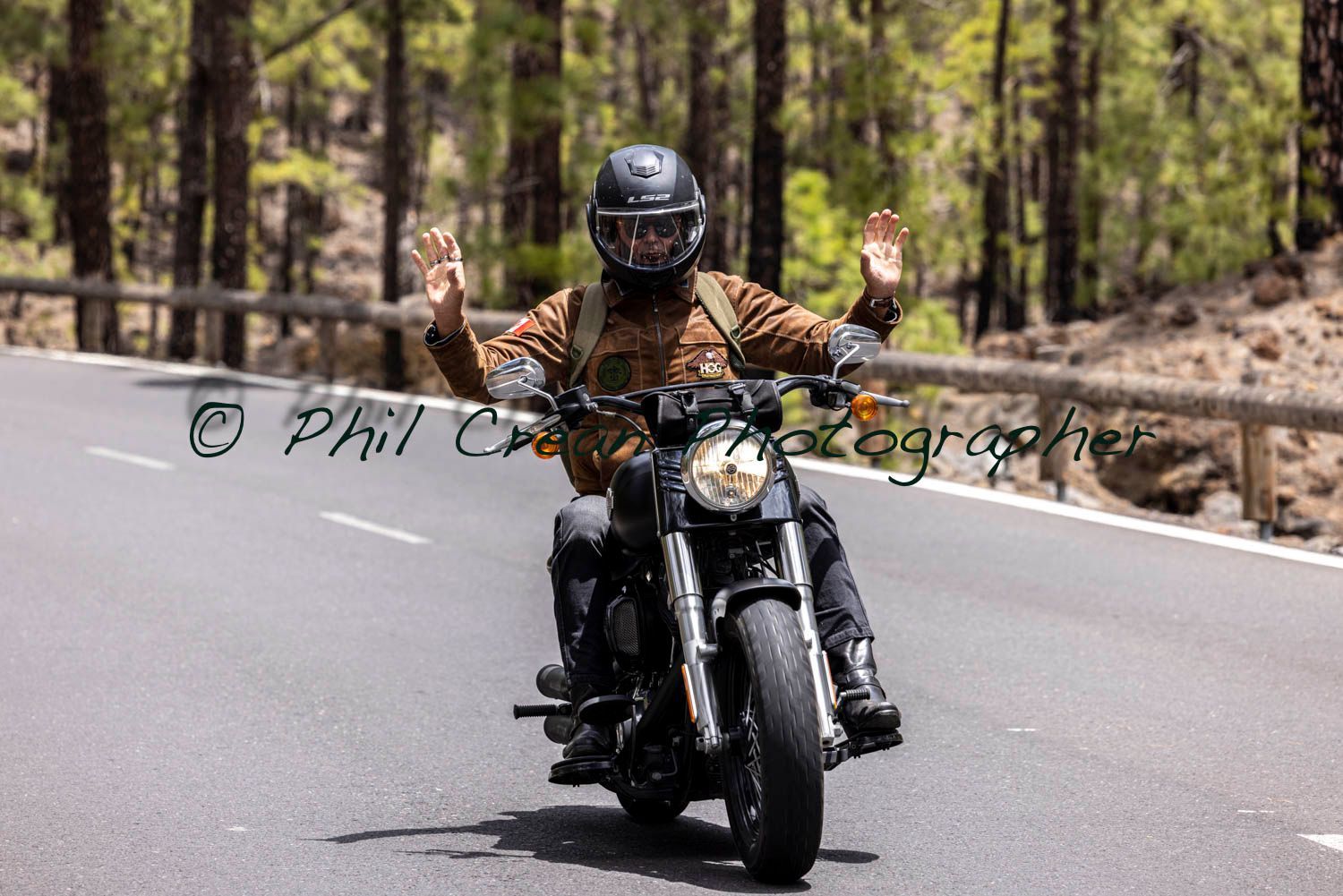 A man is riding a motorcycle down a road.