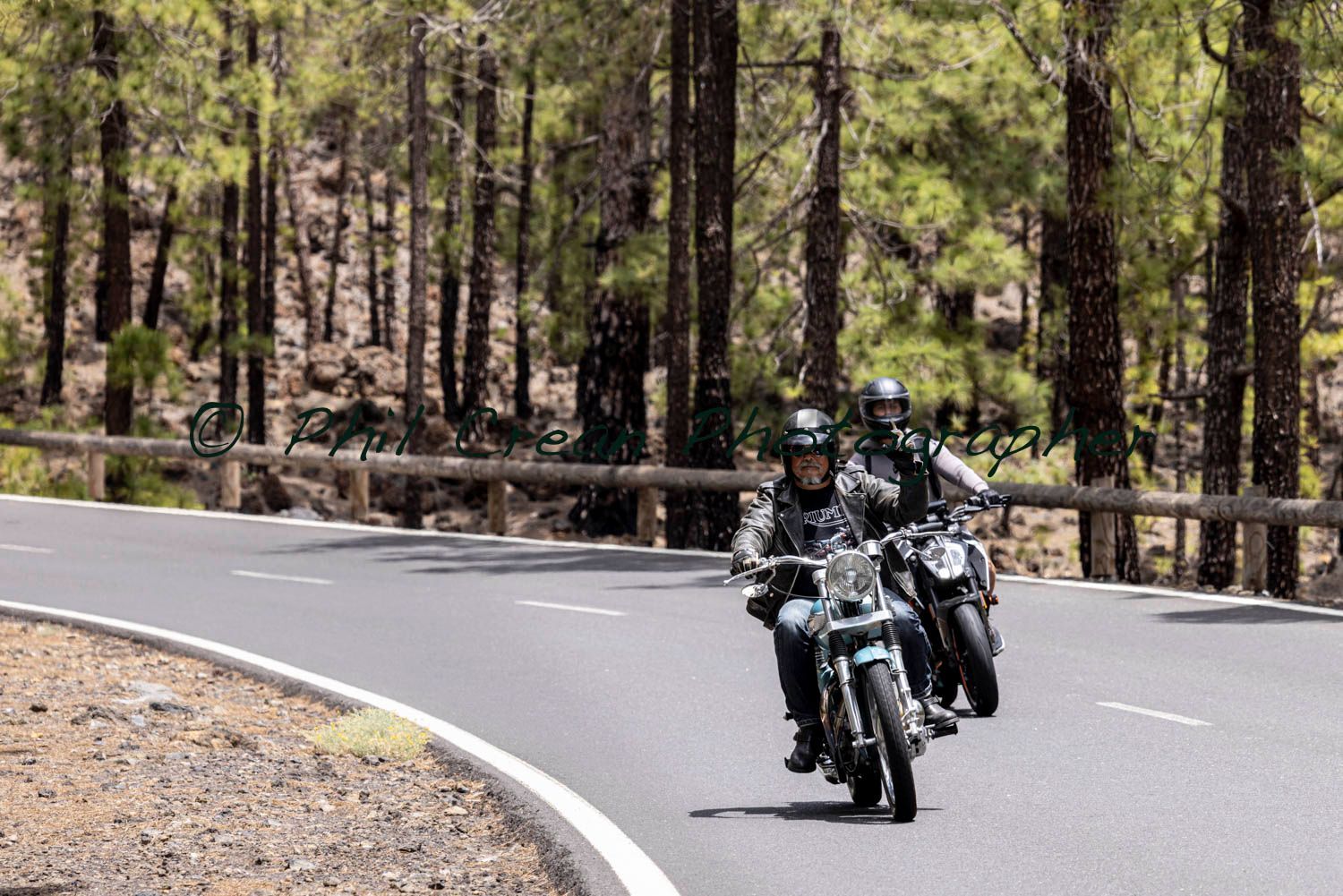 Two people are riding motorcycles down a curvy road.