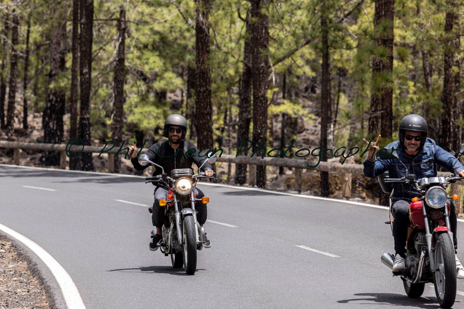 Two men are riding motorcycles down a road.