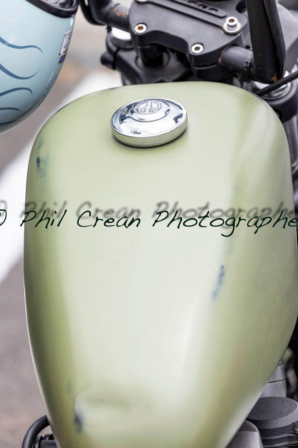 A close up of a motorcycle fuel tank with a helmet in the background