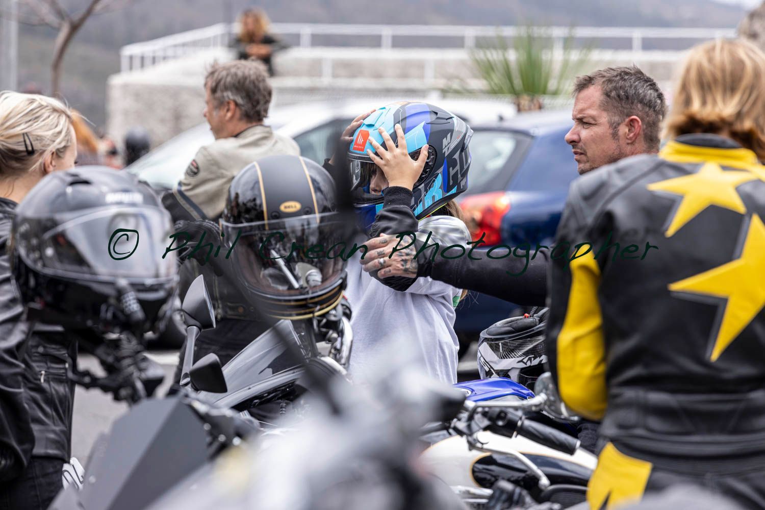 A man is helping a child put on a motorcycle helmet.