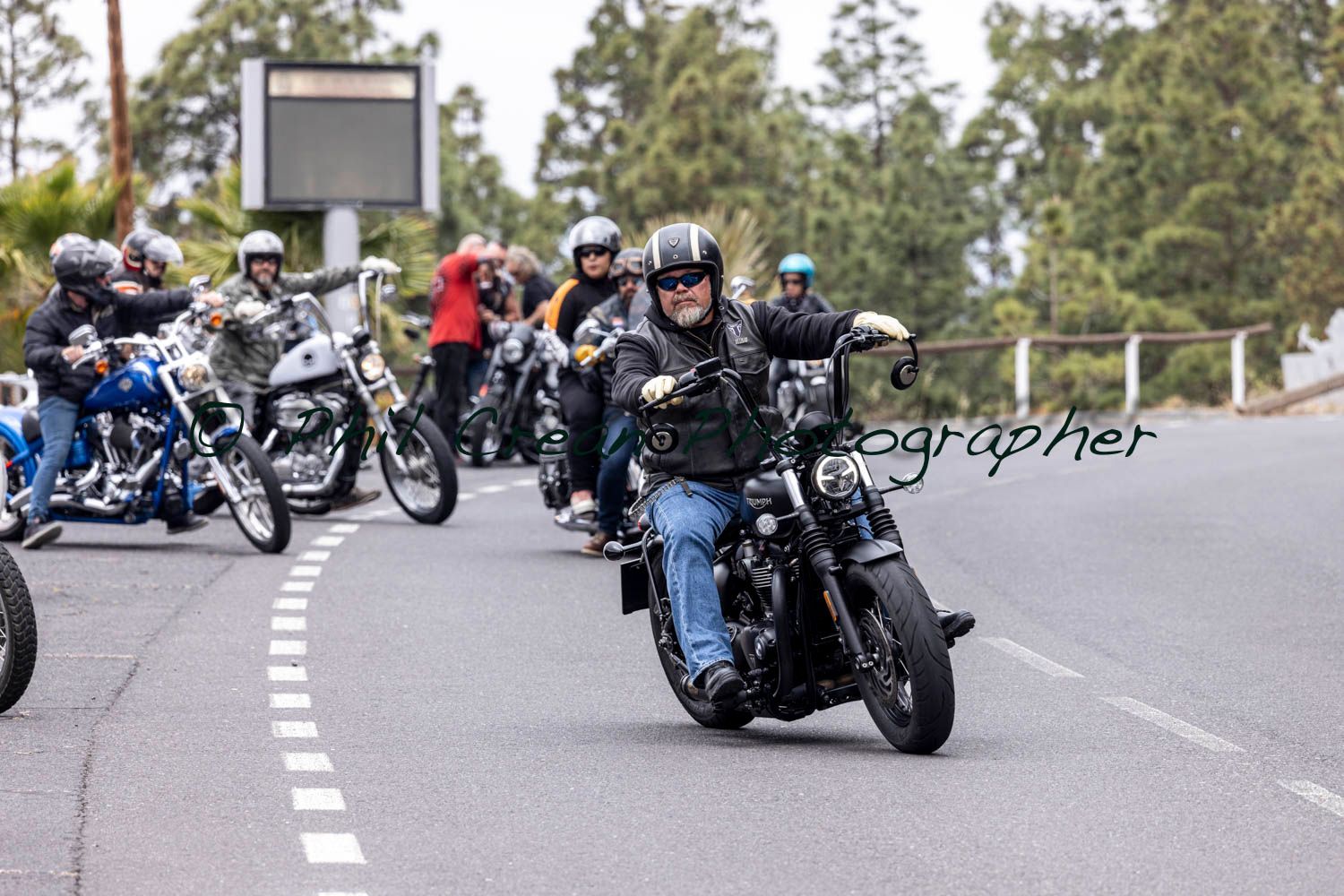 A group of people are riding motorcycles down a road