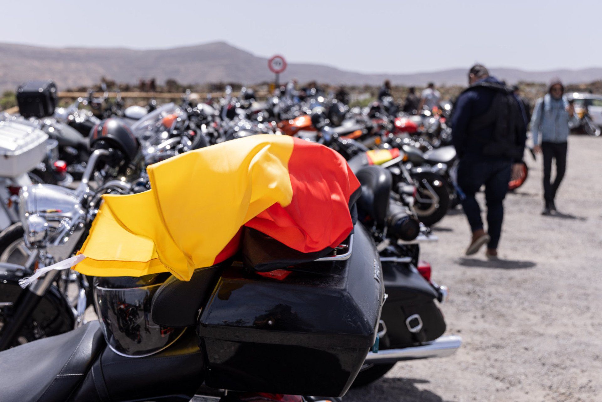 A motorcycle with a yellow and red flag on the back is parked in a parking lot.