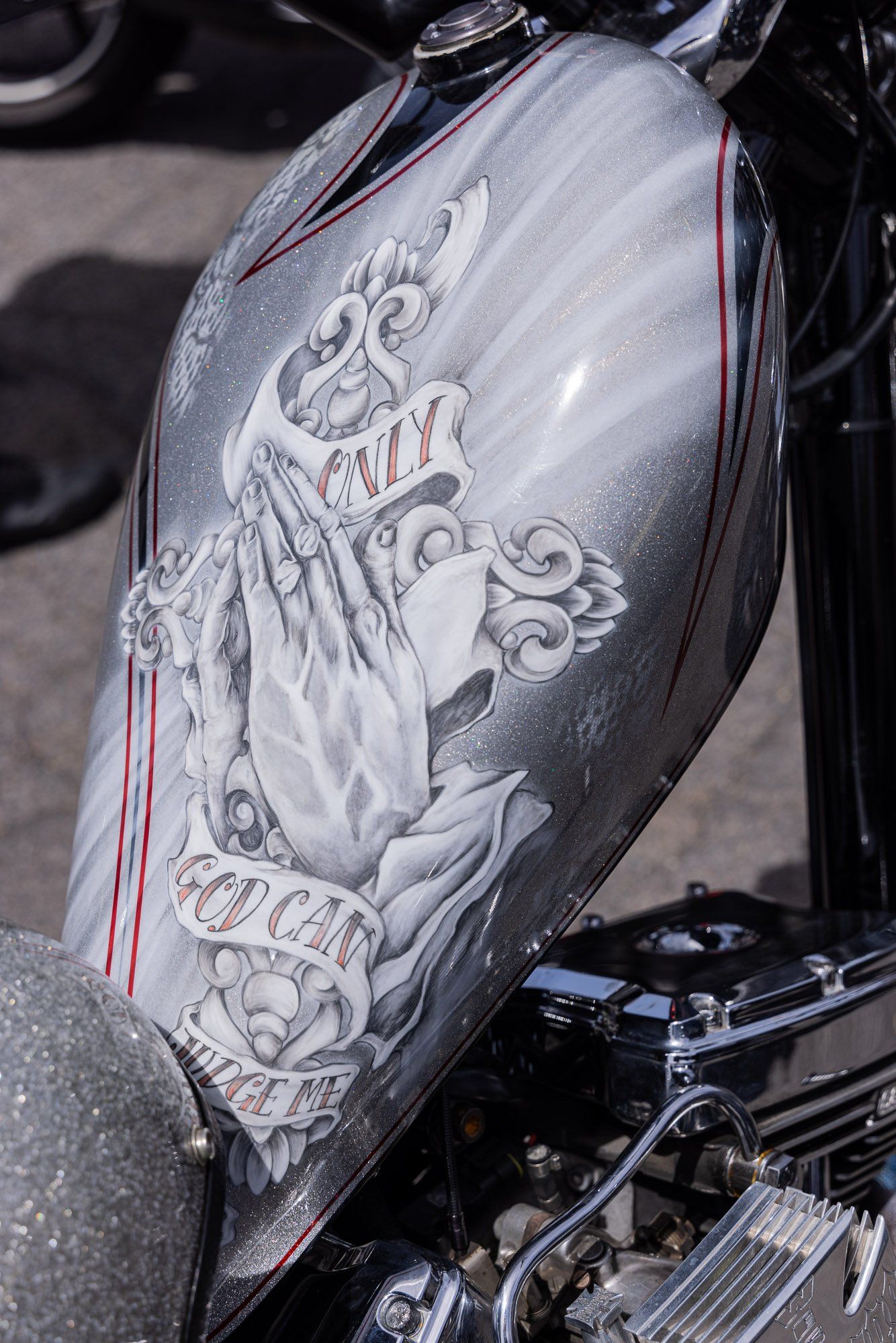 A close up of a motorcycle tank with a praying hands design on it
