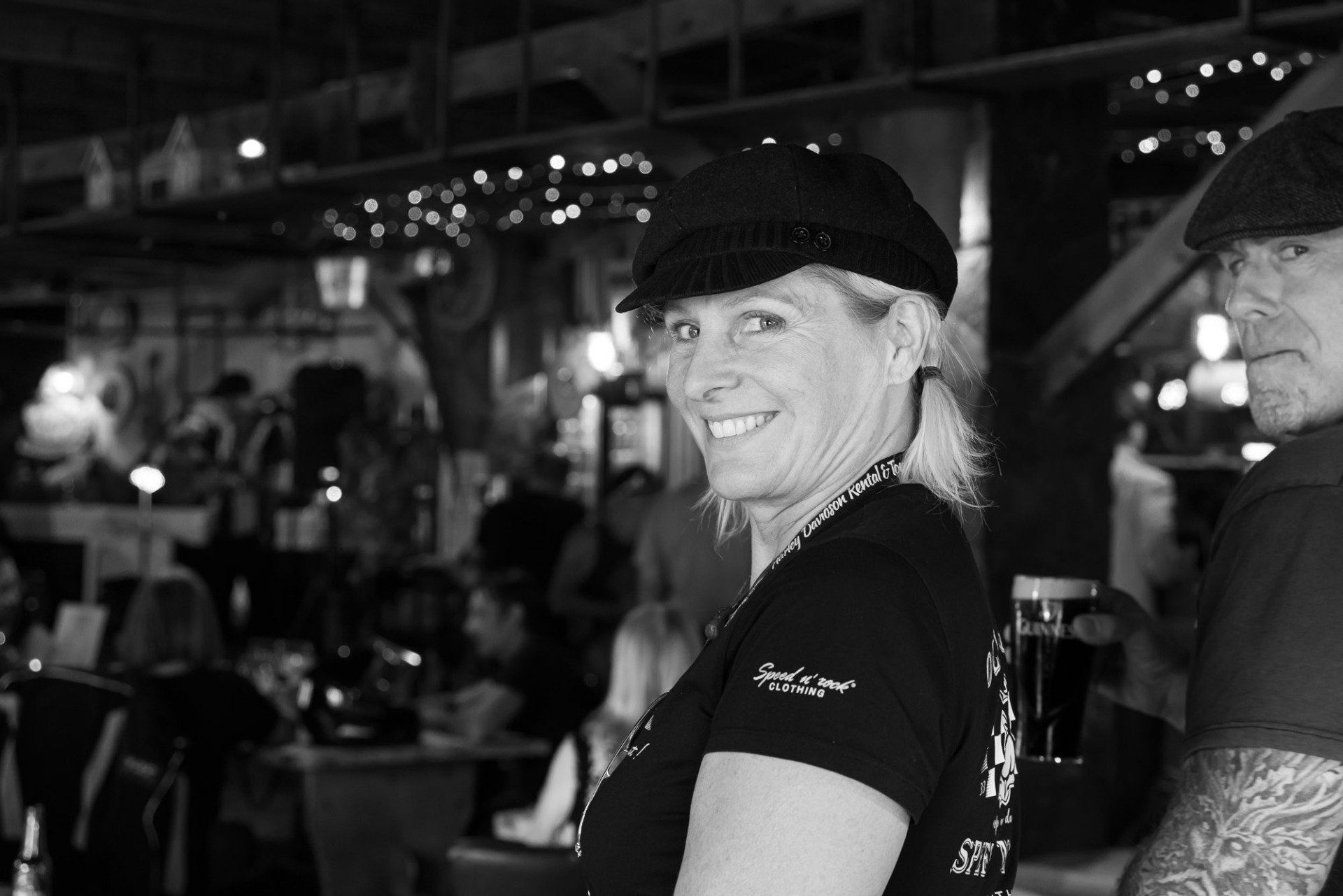 A woman wearing a hat is smiling in a black and white photo.