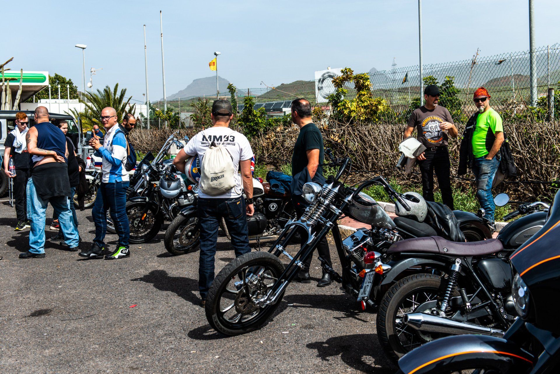A group of people are standing around motorcycles on the side of the road.