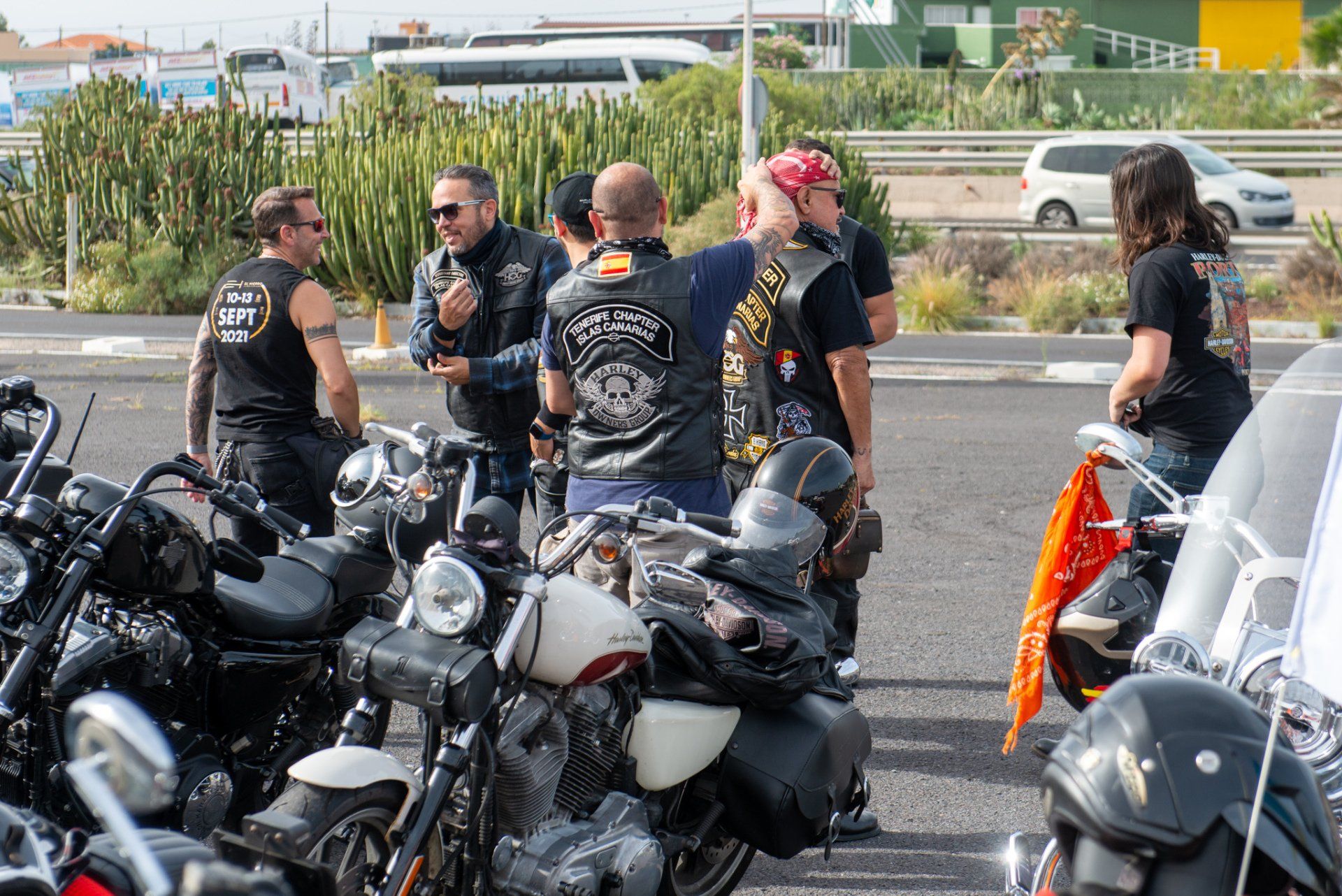 A group of men are standing around motorcycles on the side of the road.