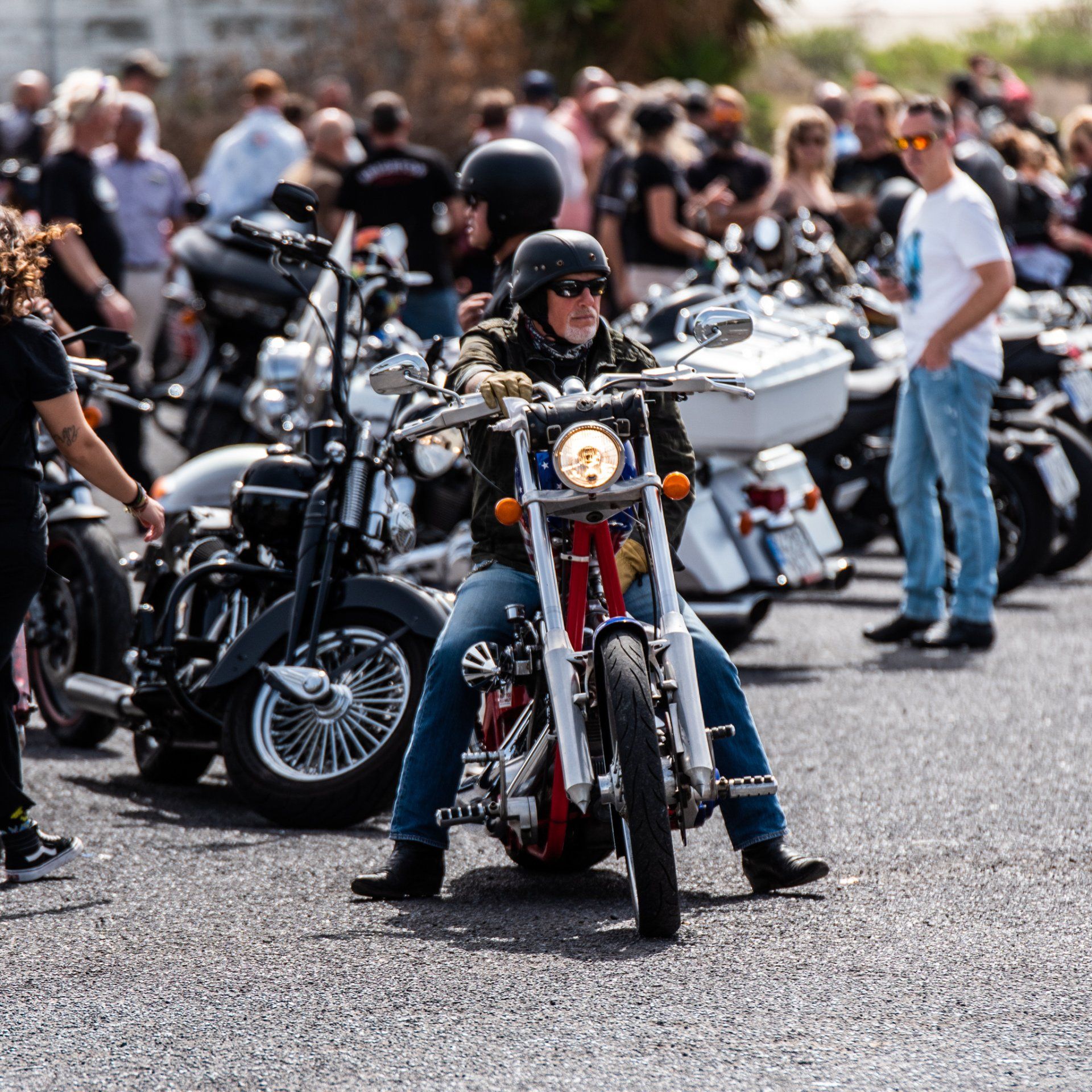 A man is riding a motorcycle in front of a crowd of people