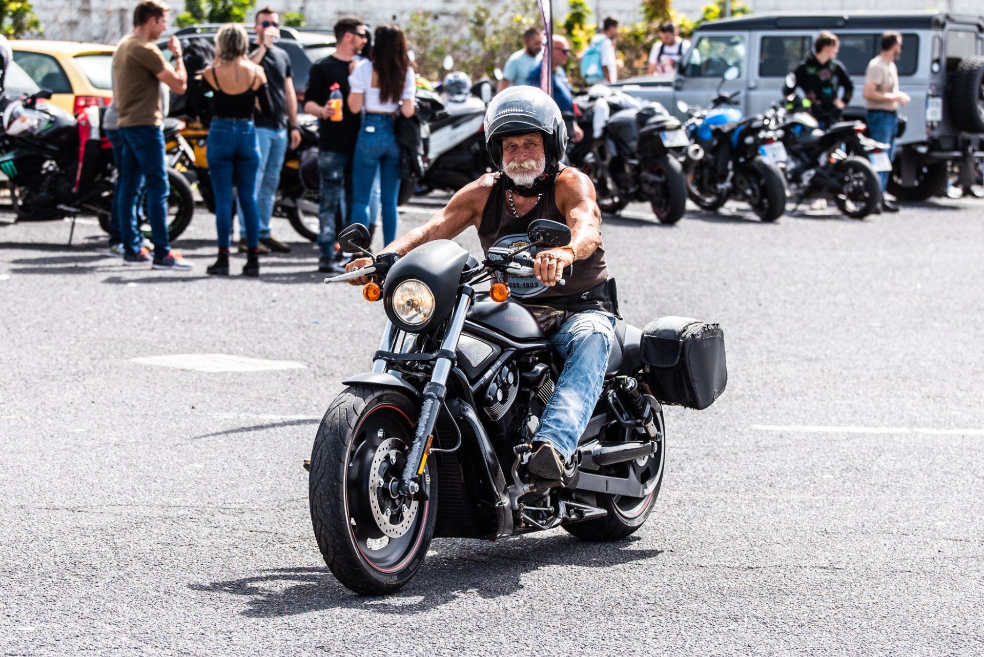 A man is riding a motorcycle in a parking lot.