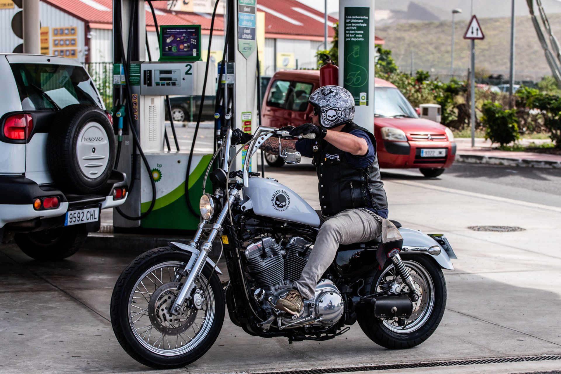 A man is riding a motorcycle at a gas station.