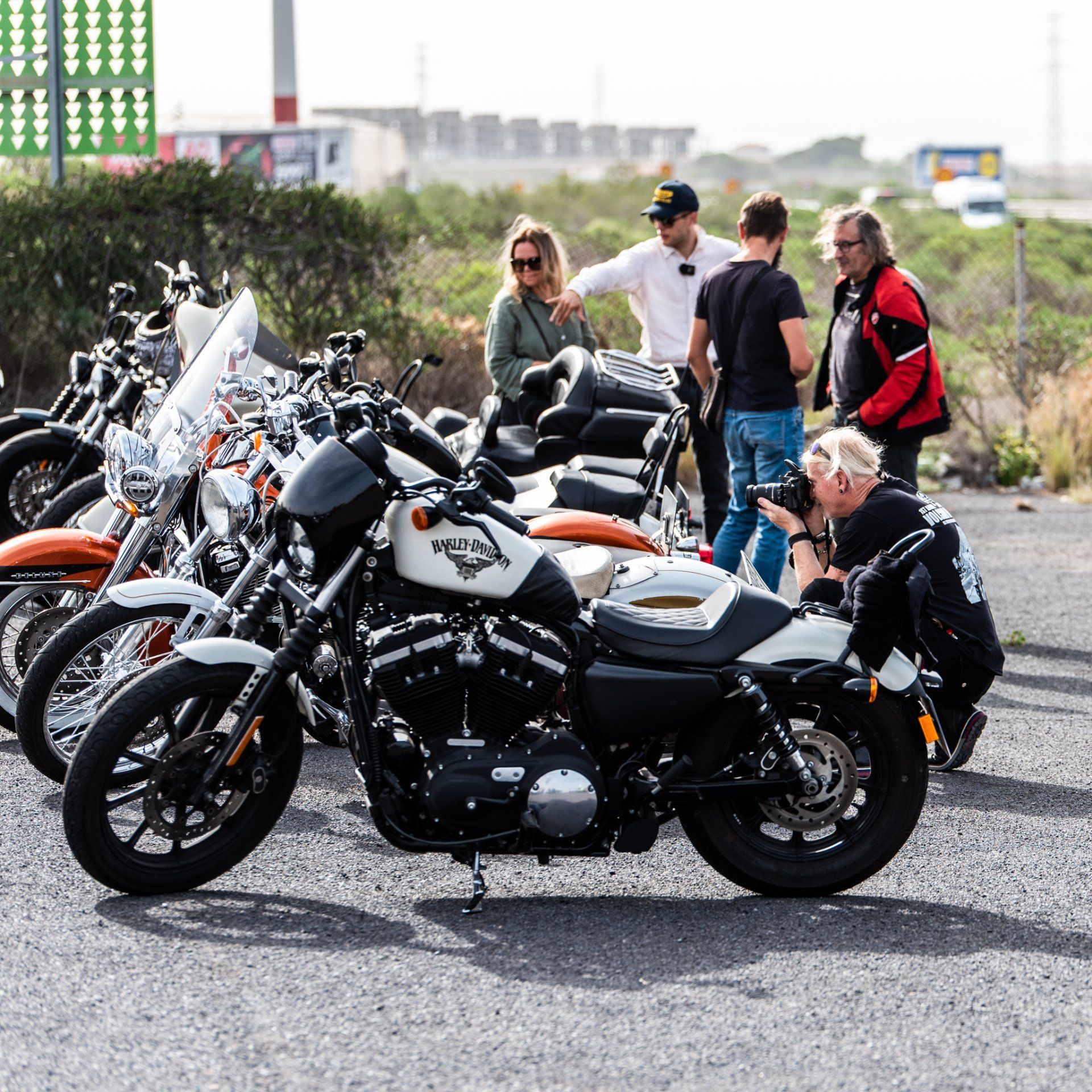 A group of people are standing around a row of motorcycles.