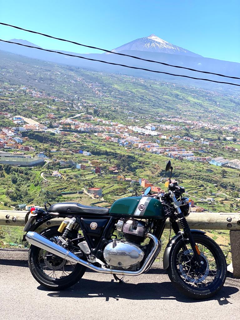 A motorcycle is parked on the side of the road with a mountain in the background.