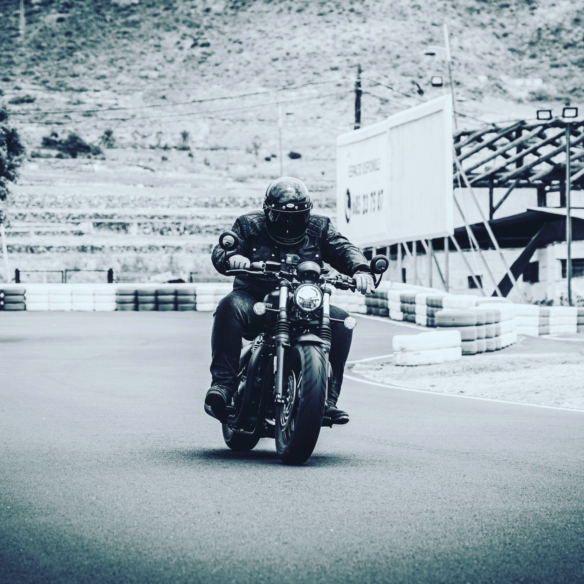 A black and white photo of a man riding a motorcycle