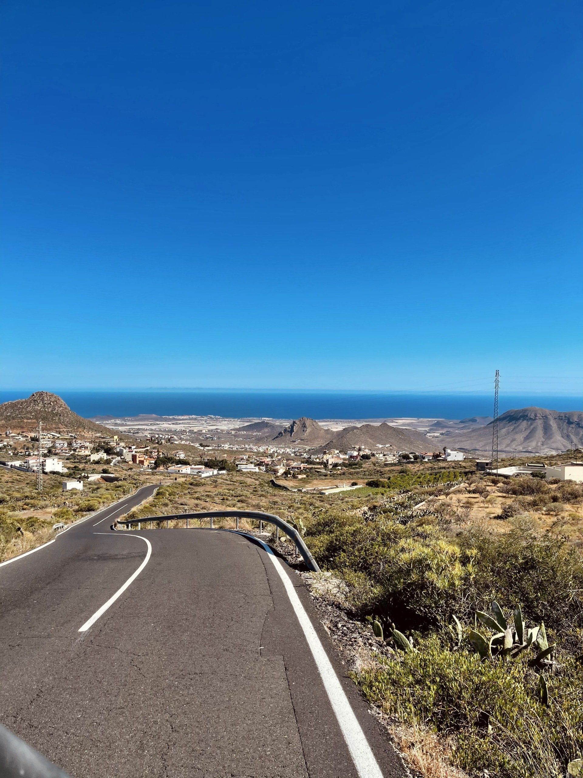 A curvy road with a view of the ocean and mountains.